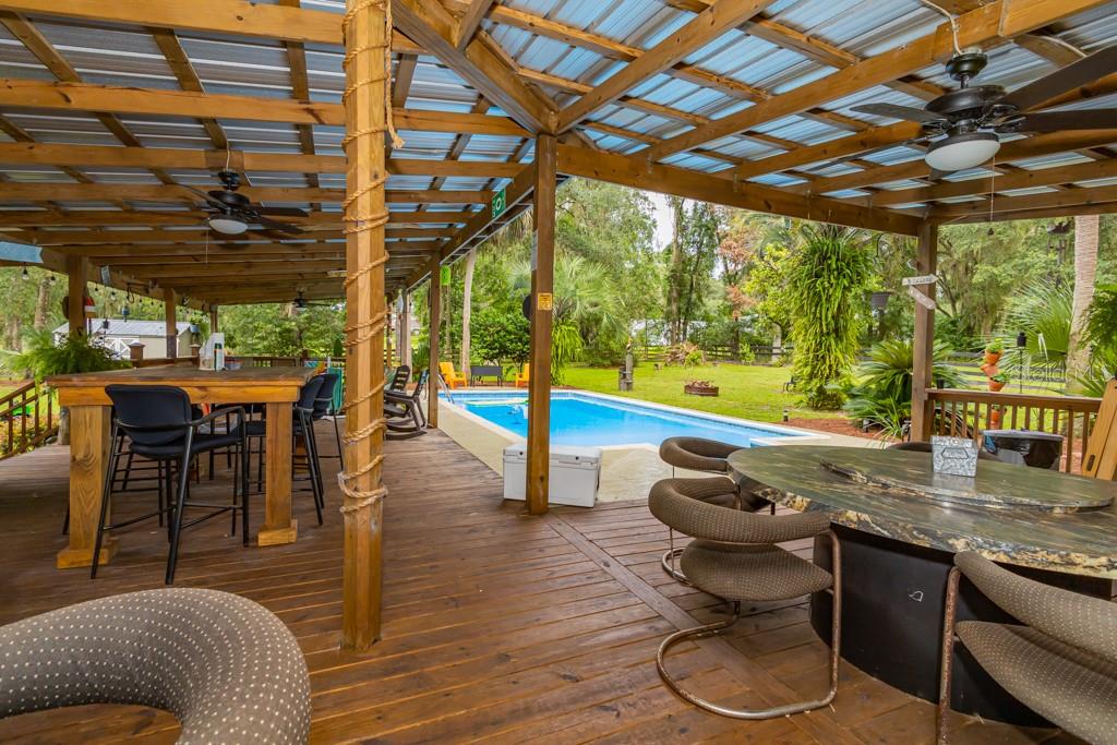 Florida living at its finest with this backyard oasis on 2 ½ acres is awaiting you to take a look.  This 4 bedroom, 2.5 bath pool home. Is truly a hidden gem. The home has been recently updated which offers both luxury and privacy just minutes from downtown Ocala. When entering the home, you notice the attention to detail with crown molding,  5 1/2 in. baseboard, 6 panel solid core doors with fluted trim, newer light fixtures, with plantation shutters on the newer windows. The kitchen is equipped with stainless steel appliances. A wine cooler, granite countertops with a breakfast bar and dining area that looks out to the stunning landscape in the front of the home.  The owner's suite is very spacious with his and her closets, frosted glass doors, double frosted barndoors lead to the spa like retreat with large shower, double vanity, and your very own makeup station. The home has a bonus room at the rear of the home with picture windows looking out to the 1400 square foot cover deck oasis. The deck has a half bath, wet bar, 2 overhead TV's, a high-top bar with electric plug ins, tons of seating areas all covered by metal roof. The soothing sound of those rainy nights! Take a swim in the 16x32 foot pool. The picturesque property backs up to a small pecan farm.  2 utility buildings are on the property.  The grounds also include a 20x20 additional building with roll up garage door, that has a side door and electric with tons of storage above. An additional 14x20 building is included that makes a total of 4 buildings on the property. Pride of ownership shows inside and out of this unique property tranquility is awaiting it is a one of a kind once you are here it is hard to leave. Enjoy everything that Ocala has to offer within minutes from biking trails, shopping, restaurants. Enjoy country living while being minutes from everything.