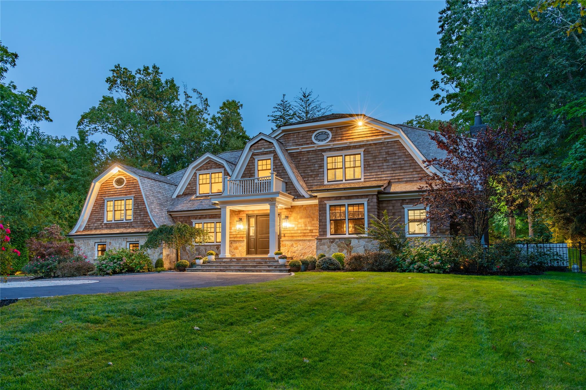 Experience the extraordinary rebirth of SERENITY, an extraordinary estate that redefines sophisticated living in the prestigious Village of Old Westbury. This meticulously renovated 2024 masterpiece represents the pinnacle of modern elegance, where every detail has been thoughtfully curated to create an atmosphere of effortless grandeur. Behind automatic gates, a sweeping landscaped drive unveils this stunning 5-bedroom, 7.5-bth shingle-style Colonial, majestically positioned on 2.06 acres of pristine grounds. The brand new cedar shingle roof crowns this architectural jewel, complementing the sophisticated stone & shingle facade that exudes timeless appeal. The Hamptons-inspired aesthetic creates a seamless dialogue between refined interiors and breathtaking natural surroundings. Step into the grand foyer where dramatic 17-ft ceilings immediately establish the home's magnificent scale. Throughout, light oak flooring creates a warm foundation for the home's refined palette, while custom millwork & soaring vaulted ceilings enhance the sense of spaciousness and light. Glass-paneled French doors reveal an intimate library-office, providing a serene sanctuary. The show-stopping double-height living room serves as the heart of the home, anchored by an elegant fireplace and framed by French doors that open to expansive bluestone patios. The formal dining room captivates with its coffered ceiling and sophisticated wainscoting, seamlessly connected to a butler's pantry featuring custom cabinetry, rich walnut countertops, integrated wine cooler, and ice maker. The chef's kitchen represents the ultimate in both form and function, showcasing custom cabinetry, luxurious Calacatta marble countertops, and premium appliances. A generous prep island anchors the space, while the adjacent breakfast area overlooks meticulously maintained gardens. The connecting family room boasts soaring ceilings, a wood-burning fireplace, and French doors that bathe the space in natural light. The luxurious primary suite occupies the west wing as a private oasis of tranquility. Double doors open to a gracious hallway leading to custom dressing closets and dual spa-inspired baths, complete with rainfall showers, jetted soaking tub, and radiant-htd floors. The serene bedroom features a vaulted ceiling and French doors opening to rear gardens, creating an intimate connection with nature. The grand staircase ascends to a 2nd floor landing with dramatic views of both foyer and living room. 4 generously proportioned bedrooms, each with en suite baths, ensure comfort and privacy for family and guests, complemented by a well-appointed laundry rm. The expansive lower level transforms into an entertainment haven, featuring an intimate media room, flexible recreation areas, dedicated fitness space, full bth, and convenient walk-out access to the grounds. The exterior spaces rival the interior's magnificence, with rolling lawns, vibrant perennial gardens, and a recently marble-dusted gunite htd swimming pool creating a private resort atmosphere. Expansive patios provide multiple venues for al fresco dining and entertaining, while mature landscaping ensures complete privacy and serenity. Premium amenities include three-car heated garage, comprehensive landscape lighting, advanced security system, central vacuum system, full irrigation system, and whole-house generator. Positioned just 25 miles from Manhattan, Old Westbury offers an unparalleled lifestyle combining suburban tranquility with urban accessibility. Residents enjoy proximity to world-class dining, luxury shopping, and prestigious country clubs, while Old Westbury Gardens and scenic equestrian trails provide recreational opportunities. The acclaimed Jericho SD further enhances this exceptional location. SERENITY represents more than a residence, it embodies a lifestyle where architectural beauty, modern luxury, and natural splendor converge in perfect harmony-This is your invitation to experience the extraordinary.