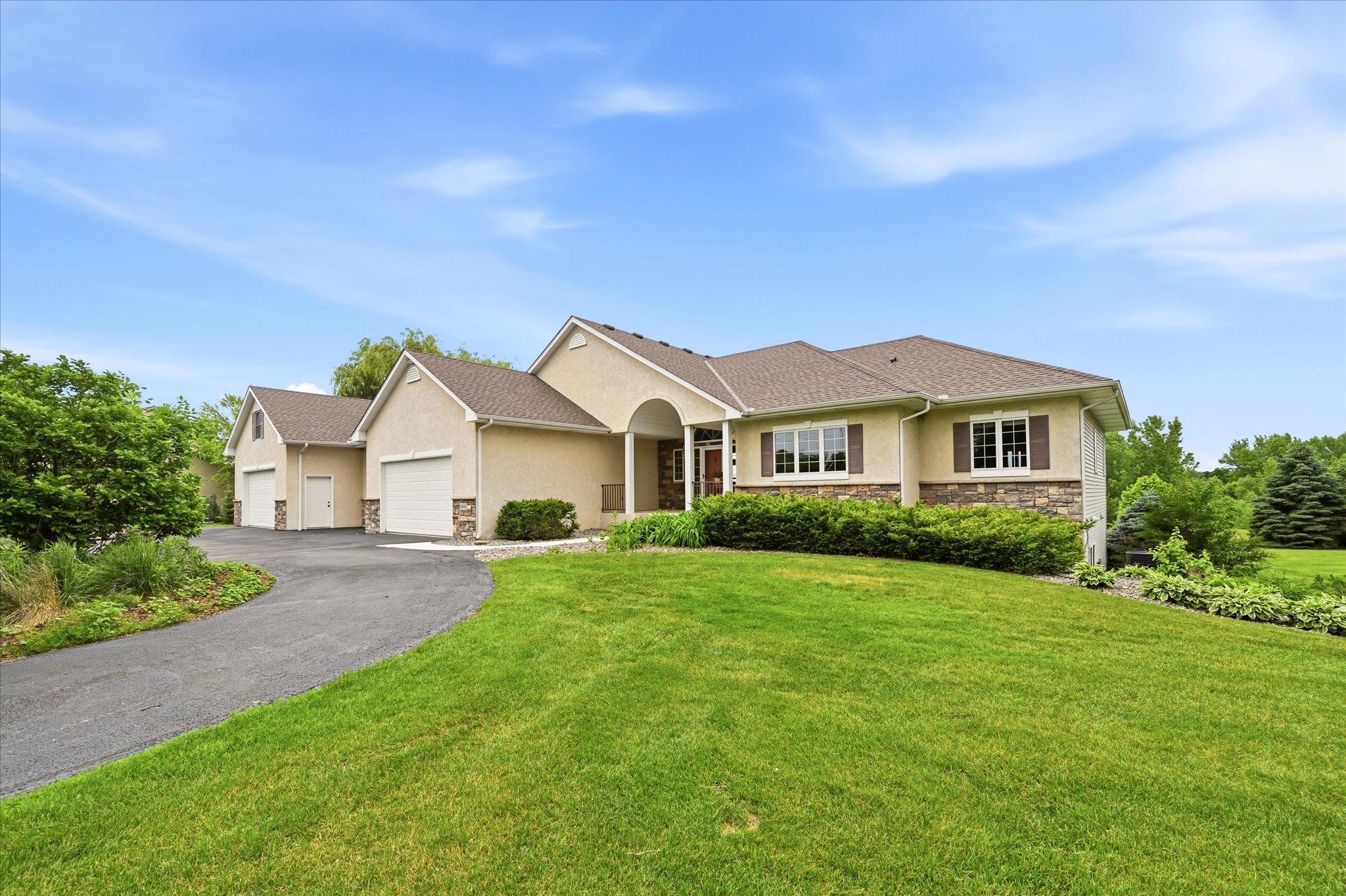 A rare find in the Bluffs of Corcoran, this walkout rambler on 2.5 acres offers a combination of privacy, space, and thoughtful updates. Surrounded by mature trees, gardens, and open views, the property is filled with natural light thanks to its abundant windows and desirable southern exposure, creating a warm and welcoming atmosphere throughout. Vaulted ceilings, hardwood floors, and a seamless flow between the foyer, living room, dining area, and kitchen create an inviting setting for both everyday living and entertaining. The living room features a stunning stone fireplace flanked by custom built-ins and expansive windows that bring the beauty of the outdoors inside. The kitchen is designed for both function and style, offering beautiful countertops, custom cabinetry, stainless steel appliances, generous storage, and ample workspace for meal preparation and gatherings. Just off the dining area, a spacious maintenance-free deck extends the living space outdoors, providing the perfect setting for morning coffee, outdoor dining, or entertaining while overlooking the peaceful backyard and surrounding landscape. The main level features two bedrooms, including a spacious primary suite complete with French doors, custom walk-in closet shelving, dual vanities, a soaking tub, and a separate tiled walk-in shower. A guest bathroom, convenient powder room with garage access, and laundry room add everyday functionality. With all essential living amenities located on the main level, the home offers comfortable one-level living. The walkout lower level provides additional living space with a large recreation room, built-in bar area, two additional bedrooms, and a beautifully updated bathroom featuring a tiled walk-in shower. One bedroom includes custom built-in shelving, offering flexibility for a home office, hobby room, or guest space. Sliding doors lead directly to the patio and expansive backyard, creating multiple areas for outdoor entertaining, recreation, and relaxation. A standout feature is the impressive 5-car garage, including a heated addition with radiant in-floor heat and an overhead heater. Above the garage, a spacious 36' x 12' bonus room offers endless possibilities for hobbies, creative pursuits, fitness equipment, workspace, or additional storage. Numerous updates provide peace of mind: roof in 2020, air conditioning 2022, three updated bathrooms 2023, updated railing and banister 2023, on-demand water heater 2025, water softener 2026, maintenance-free deck 2026, and recent garage improvements 2026.