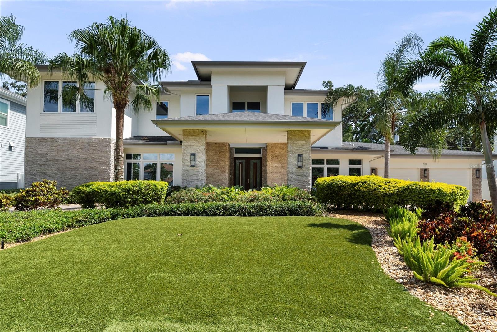 As you approach this stunning custom residence by Taralon Homes, a stately porte-cochère and circular brick driveway create a grand first impression, setting the stage for the refined elegance that lies within. Situated on a large, elevated lot with an expansive front lawn featuring manicured artificial turf and lush, tropical landscaping, the home enjoys a commanding presence just moments from Bayshore Boulevard. This contemporary masterpiece offers over 4,700 square feet of thoughtfully designed living space that seamlessly blends modern sophistication with everyday comfort.
A rare luxury in South Tampa, the oversized 4-car garage offers ample room for guests, a car collection, or additional storage needs.

Inside, every detail reflects quality and intention—from elegant custom lighting and designer fixtures to a floorplan that balances luxurious living with practical functionality. The home features five spacious bedrooms, three and a half bathrooms, a private study, an entertainment loft, a flexible multi-purpose room perfect for a gym, nursery, or second office, and generous storage throughout. Gently lived in, the home remains in pristine, like-new condition.


At the heart of the home is the spectacular chef’s kitchen, outfitted with sleek European-style cabinetry, quartz countertops, and high-end JennAir gas appliances. Three oversized islands serve distinct purposes—preparation, serving, and socializing—making this space ideal for entertaining and everyday living. Soaring ceilings with designer custom detailing and recessed lighting enhance the expansive open-concept layout.

Indoor-outdoor living is elevated by a dramatic 90-degree sliding glass wall that opens to a breathtaking two-story screened lanai. This private outdoor retreat features a gas-heated spa, dual-sided fireplace, built-in gas firepit, and a fully equipped outdoor kitchen, all set among travertine pavers, manicured artificial turf, and full privacy fencing.

Modern technology and peace of mind are seamlessly integrated throughout the home. A whole-house Control4 system manages smart home functions, including the thermostat control, with all equipment discreetly housed in its own dedicated room. Additional features include a security system with cameras and a whole-house natural gas generator for enhanced safety and convenience.

Located in Flood Zone X—no flood insurance required.

This is more than a home—it’s a curated lifestyle in one of South Tampa’s most desirable neighborhoods.