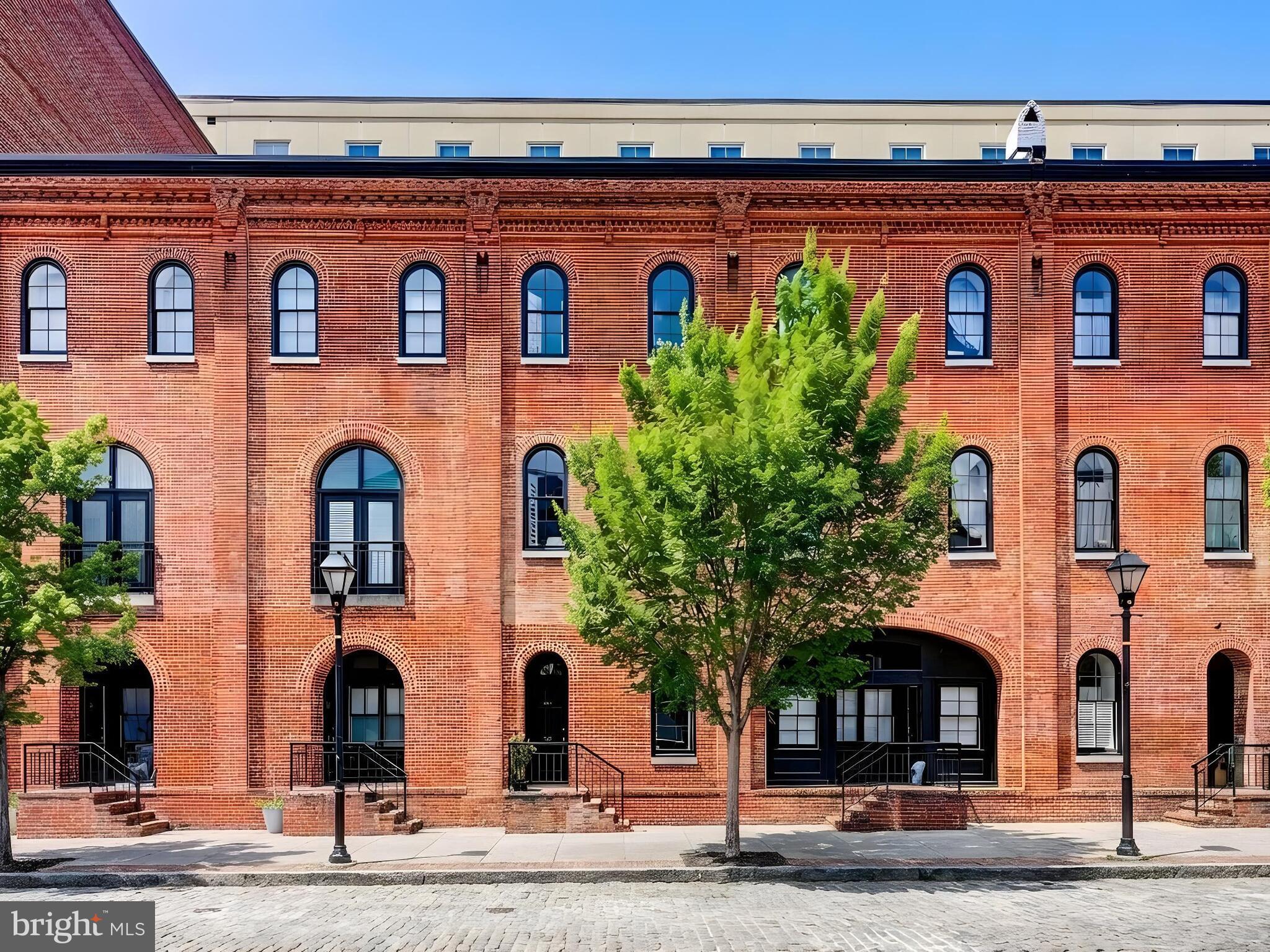 Welcome to Belt’s Landing, a premier waterfront condominium community in idyllic location, offering a rare townhome-style residence with three finished levels, two-car garage parking, and exceptional amenities. Tucked along a charming Belgian block street just steps from the waterfront promenade, this two-bedroom, two full and one-half bath home spans over 1,700 square feet and blends privacy, security, and walkability in the heart of historic Fells Point. Bright, airy interiors unfold across three levels with generous living and entertaining spaces. One of the beautiful features of this home is walking out the front door into the heart of Fells Point while retreating through a rear door to the amazing amenities of the condominium including the parking only steps away.  The brick façade and arched entry with black trimmed windows and doors creates a sophisticated feel when entering the sun-filled living room centered on a wood burning fireplace with handsome custom built-ins with a charming bench seat. The main level flows through a dining area and into a beautifully designed kitchen featuring white cabinetry, stainless steel appliances, and natural stone countertops.  A powder room and a large coat closet complete the first level. The two upper levels offer excellent separation of space with two distinct bedroom levels, including a primary suite retreat with two walk-in closets and a refined bathroom with a dual vanity, walk-in shower, and a beautiful pedestal soaking tub. The third-level offers a second bedroom with a well-appointed bathroom and a landing area which provides flexible space ideal for a home office or reading area. Thoughtful updates include Brazilian mahogany floors, a wood burning fireplace, plantation shutters, closet organizers, and accent lighting. Belt’s Landing residents enjoy 24-hour security, concierge service, a harbor-view outdoor pool, fitness center, billiard room, outdoor community patios, and well-maintained common areas, all moments from Fells Point’s renowned dining, boutiques, and waterfront experiences, offering a rare opportunity for lock-and-leave convenience, comfortable living, and classic Baltimore charm.