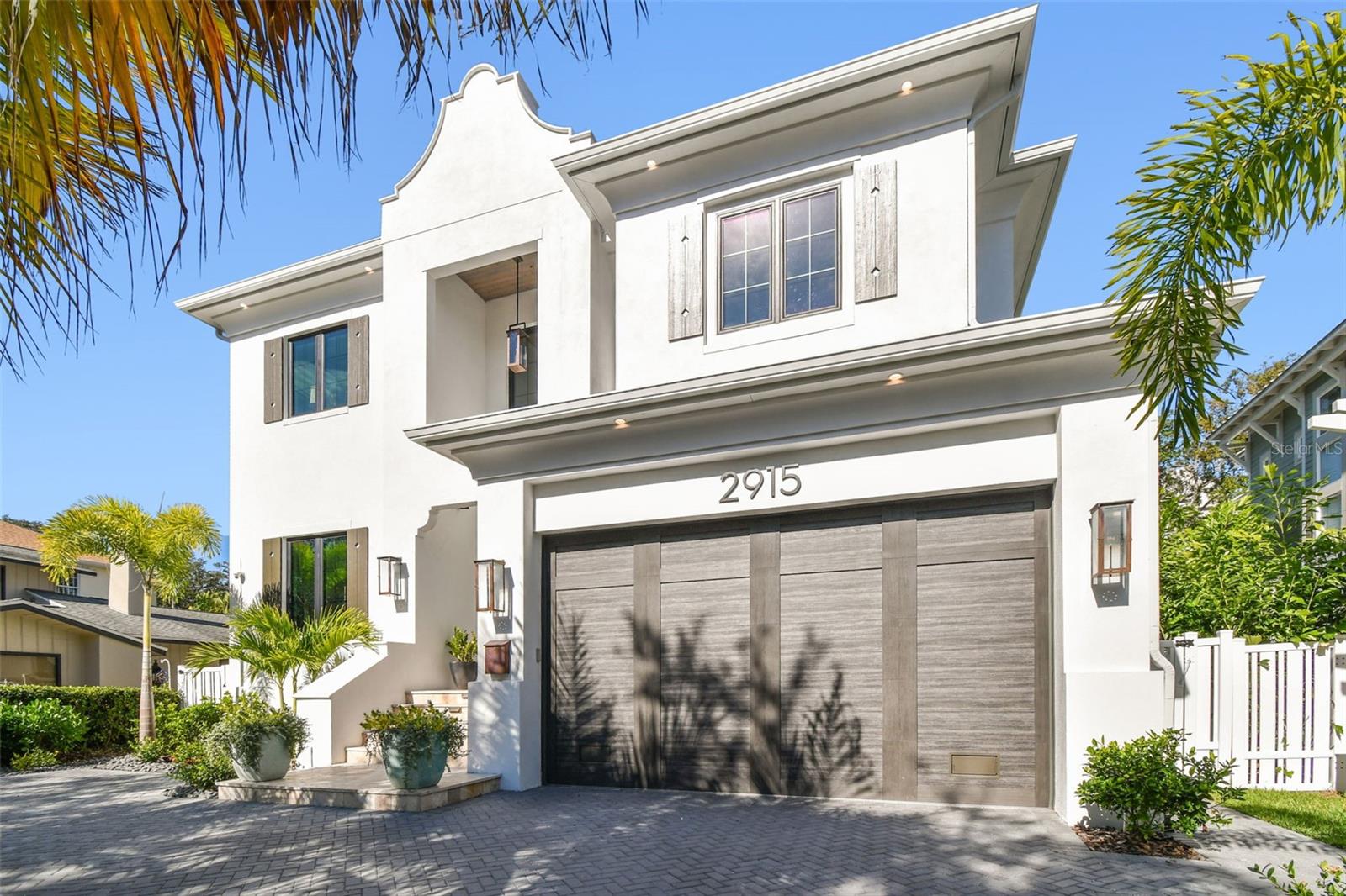 Ideally positioned on a picturesque, sidewalk-lined street in the heart of Bayshore Beautiful, just moments from iconic Bayshore Boulevard, this nearly new custom residence by Taralon Homes delivers refined architectural presence and elevated living throughout. A pavered circular drive, travertine entry steps, and classic Bevolo gas lanterns create a striking arrival. Inside, a grand foyer with soaring ceilings and statement Restoration Hardware lighting introduces an open, light-filled floor plan with 7.5" naturally aged Medallion wide-plank flooring, 8' solid-core interior doors, and level-five smooth drywall. Formal dining with custom built-in cabinetry and a full wet bar featuring Sub-Zero refrigeration and a wine fridge anchors the main level alongside an expansive great room. This room is highlighted by a marble-clad electric fireplace wall and wall-length sliding glass doors that open seamlessly to the outdoors. The chef’s kitchen pairs sculptural design with exceptional function, featuring a dramatic marble waterfall island, dual Thermador refrigerators, a six-burner Thermador gas range with custom hood, galley sink with on-demand filtered water, under-cabinet lighting, and built-in refrigeration drawers. A secondary wet bar with wine refrigeration and ice machine connects directly to the outdoor bar, while a fully equipped scullery with marble counters, additional dishwasher, and walk-in pantry provides discreet convenience. A custom drop zone with built-ins sits just off the garage. Indoor-outdoor living is effortless at the covered lanai with travertine flooring, drop-down screens, recessed lighting, speakers, and a fully appointed alfresco kitchen, overlooking the heated saltwater pool and spa framed by lush landscaping and hardscape. Upstairs, a flexible media lounge with custom cabinetry and wet bar complements generously sized secondary suites with custom closets and marble-finished en-suite baths. The primary suite is a serene retreat with coffered ceilings, dual custom walk-in closets, and a spa-inspired bath featuring a soaking tub, oversized walk-in shower with jewel showerheads, marble vanities with makeup station, towel warmer, and Toto fixtures. Additional highlights include elevator access to all levels, impact-rated windows and doors, spray-foam attic insulation, two natural-gas wall-mounted tankless water heaters, pre-wired low-voltage security and surround sound, Lutron lighting, integrated speakers, owned security cameras, a pool bath with marble waterfall vanity, and a spacious laundry room with built-ins. The two-car garage with lift offers epoxy flooring, rear yard access, and integrated irrigation controls. Enhanced by a Generac whole-home generator and meticulous attention to detail, this exceptional residence offers timeless luxury just steps from Tampa’s most celebrated waterfront promenade.