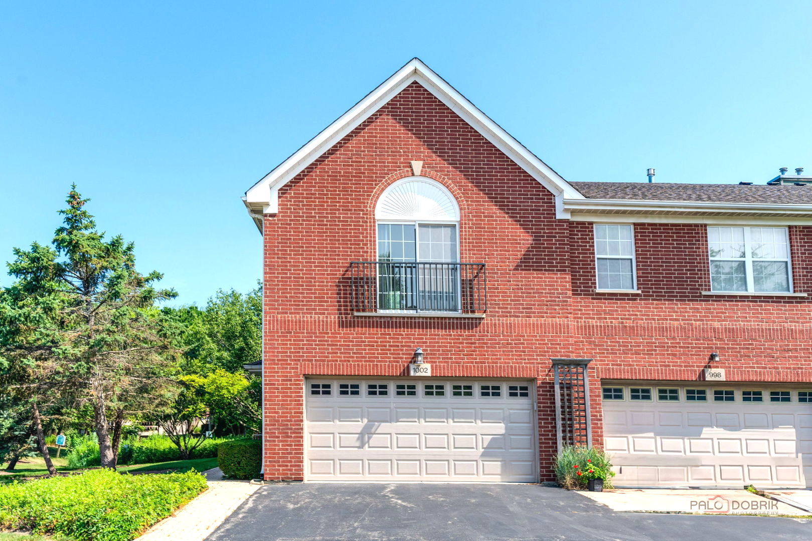 Welcome to this bright and spacious end-unit townhouse in the highly desirable Northbrook Green subdivision! This well-maintained second-floor home features 2 bedrooms, 2 full bathrooms, and an open, functional floor plan filled with abundant natural light. Enjoy your morning coffee or unwind after a long day on the private balcony overlooking a peaceful pond with a beautiful fountain. The spacious primary suite offers a vaulted ceiling, a walk-in closet, and a private en-suite bath with a soaking tub, separate shower, and double vanity. A unique three-sided fireplace adds warmth and character to the living and dining areas, creating a bright and inviting atmosphere. The attached 2-car garage features durable epoxy flooring, additional storage space, and a new garage door and opener (2025). A new water heater was installed in 2026. Ample nearby guest parking provides added convenience for family and visitors. Ideally located just minutes from shopping, dining, Metra, parks, and highly rated schools, this home offers the perfect blend of comfort, convenience, and location. Whether you're looking for a place to call home or a low-maintenance lifestyle in one of Northbrook's most sought-after communities, this inviting townhouse is ready to welcome its next owner. Don't miss this wonderful opportunity!  The home has been well maintained and is being sold AS-IS. The price reflects its original finishes and provides an excellent opportunity for the next owner to add modern updates and personalize the home to their taste.