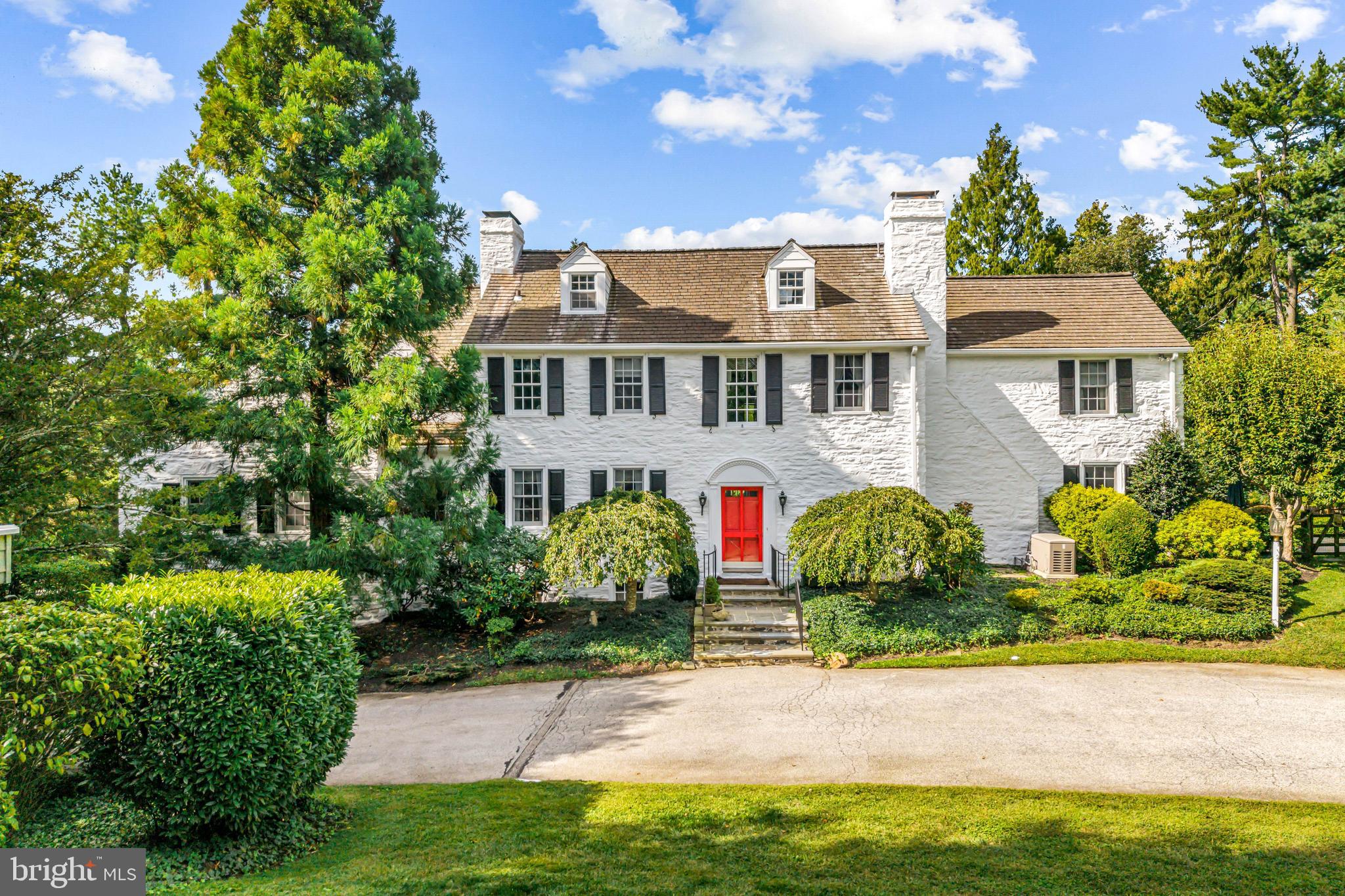 Surrounded by pastoral beauty and across from preserved land, this classic 1930s Main Line estate blends privacy with convenience in one of Gladwyne’s most desirable settings. The painted white stone exterior with black shutters captures timeless character on 2.47 acres with sweeping lawn and mature landscaping. 1324 Youngsford Road encompasses a main residence with 7,112 square feet on three levels—five bedrooms, five full and one half bath—along with a two-bedroom, two-bath carriage home. Combined home and carriage house offers 7 beds, 7.5 baths,The main level showcases  distinguished spaces, where old-world character meets architectural detail. A slate walkway with wrought-iron railing leads to the front entry, opening to a foyer that introduces gracious gathering rooms. Straight ahead, the dining room is framed by a wide triple window, creating a beautiful setting for formal dining. To the right, the living room impresses with wide-plank hardwood floors, soaring ceilings, and a paneled fireplace surround that reflects the home’s craftsmanship. French doors open to a side slate terrace with a stone sitting wall overlooking the pool and gardens, while expansive windows and doors throughout this level flood the rooms with natural light. From the living room, two openings connect to the striking family room addition by renowned builder E.B. Mahoney. Distinguished by generous proportions, hardwood floors, and a wall of windows, this light-filled space is the heart of the home. A second fireplace adds warmth, while French doors extend the living space outdoors. A hall off this room houses a three-stop elevator serving the lower level and primary suite. A cozy sitting room with built-ins and the home’s third fireplace provides an intimate retreat, while a powder room is conveniently placed off the foyer. The sunny kitchen offers three windows, a side door, and an adjoining breakfast nook with a bay window for casual meals. This wing also includes an office, laundry room, full bath, and rear staircase. While functional, these spaces offer opportunities for customization or a more open layout.Upstairs, the expansive primary suite spans an entire wing with a spacious bedroom, walk-in closets with built-ins, and a sitting room that can serve as a home office or quiet retreat. The en-suite bath includes a large vanity and water closet, with space for updating. Bedrooms two and three share a Jack-and-Jill bath, while bedroom four enjoys its own en-suite bath and walk-in closet. The third floor features a fifth bedroom with en-suite bath—ideal for a guest or Au pair suite. All bedrooms are carpeted, with hardwood flooring underneath awaiting refinishing.The walk-out lower level offers a recreation room with slate floors, panelled walls, beamed ceilings, a bar, and the home’s fourth fireplace. French doors open to a slate patio and the rear yard, providing access to the pool and gardens for entertaining. Storage areas, utilities, and interior access to the side-entry two-car garage complete this level.A separate carriage house provides 1,581 square feet of flexible space with living, dining, kitchen, bedroom, and full bath on the main level, plus a second bedroom and bath upstairs. Ready for cosmetic updates, it offers versatility for guests, in-laws, or business use, supported by the property’s license. Outdoor amenities include a pool with patio and greenery, a stone pool house, and expansive lawns with mature landscaping that create a picturesque setting.With timeless architecture, distinguished spaces, and strong bones to be re-imagined, this is a rare opportunity to own a standout home in one of Gladwyne’s most coveted settings. Just half a mile from the Village of Gladwyne and close to Kenealy Nature Park, the Bridlewild Trail, and award-winning Lower Merion schools, the property offers both tranquillity and accessibility. Narberth Station is three miles away with service to Philadelphia and New York.