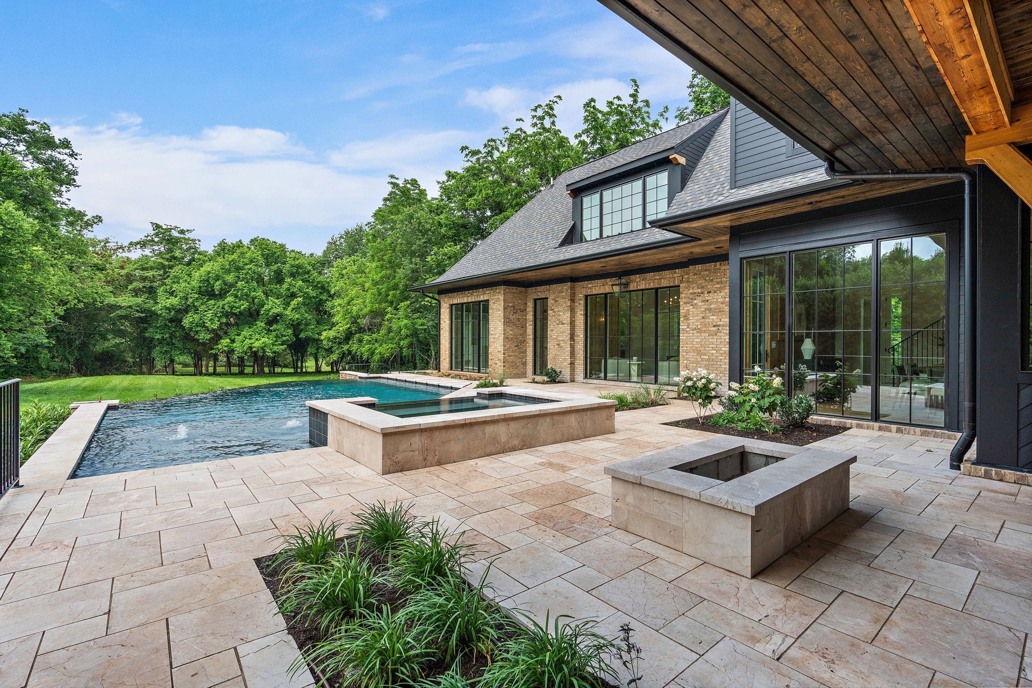 This stunning French Country–inspired estate blends timeless elegance with modern luxury. Situated on 1.2 flat acres, the home features 11-foot ceilings on the main level and 9-foot ceilings upstairs, creating a spacious and airy feel throughout.Designed for both everyday living and grand entertaining, the residence offers a three-car garage with a custom porte-cochère, and a heated gunite infinity-edge pool, spa, and firepit—truly an entertainer’s dream.Inside, you’ll find designer finishes, Signature Hardware fixtures, and a turnkey interior ready to impress. The chef’s kitchen is outfitted with Miele and KitchenAid appliances, a marble island, and an open layout that flows beautifully into the living and dining spaces.Enjoy the luxury of two primary suites on the main floor, ideal for multigenerational living or hosting guests in comfort and style.Soaring floor-to-ceiling windows and a spectacular arched front door flood the home with natural light, offering serene views of the lush landscaping and pool beyond.