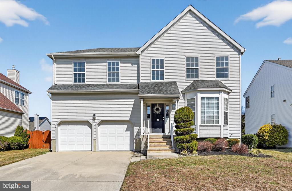 Welcome to 20 Colts Gait Road, a spacious two-story colonial offering soaring ceilings, a flexible floor plan, and the opportunity to bring your own vision to a well-designed home. A concrete driveway leads to the two-car garage, and a small covered front porch welcomes you inside. Step into the two-story foyer, where the staircase and second-floor overlook create an open and inviting entrance. To the right of the foyer, you'll find the formal living room featuring a large bay window overlooking the front yard, which flows into the formal dining room. The dining room provides an inviting space for everyday meals or hosting gatherings and is open to the adjoining living area, creating a natural flow for entertaining. From the dining room, continue straight ahead to the main-floor laundry room with shelving for storage, while a slight turn to the left leads into the kitchen. Heading down the hallway from the front entrance, you'll pass the coat closet and powder room before arriving at the eat-in kitchen, featuring stainless steel appliances, a gas stove, and oak cabinetry and a pantry closet that provide generous storage. The kitchen opens to the two-story family room with a wood-burning fireplace featuring a marble surround and large windows that fill the space with natural light. Sliding glass doors lead to a tiered wood deck (as-is) overlooking the backyard, where fencing is already in place along the rear and sides of the property. The home also features a full unfinished basement, offering generous storage and excellent potential for additional living space. Upstairs, the home currently offers three bedrooms and two full bathrooms. Originally designed as four bedrooms, two rooms were combined to create an additional primary suite with double closets and a private bath. The original primary suite features two closets, including a walk-in and an additional double closet, along with a spacious bathroom offering a soaking tub and a full walk-in stall shower with a sliding glass door. The additional primary suite offers a walk-in closet along with an additional open closet with rack storage and convenient access to the hall bathroom, featuring a full walk-in tiled shower with a sliding glass door. Each bedroom offers abundant natural light, generous closet space, and ceiling fan light fixtures, creating comfortable and functional living spaces. With its spacious layout, natural light, and flexible floor plan, this home offers a wonderful opportunity for the next owner to personalize the space and make it their own. Colts Run residents enjoy access to a community park, tennis courts, basketball court, and a walking/jogging path. The neighborhood is conveniently located just minutes from shopping and dining, with quick access to Routes 70, 73, I-295, and the NJ Turnpike, making commuting easy.