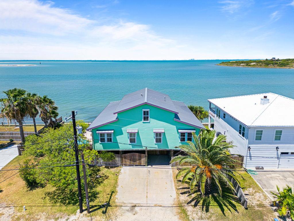 Your coastal oasis at Ingleside on the Bay! This stunning waterfront home offers panoramic views of the sparkling bay, immediate access to the Corpus Christi Channel, and postcard-worthy vistas of Ingleside Point. Situated on an oversized lot, it's designed for both relaxation and adventure. Enjoy a bayside pool perfect for warm Texas afternoons, plus expansive covered entertaining areas downstairs for gatherings day or night. An extra-wide bulkhead invites you to fish from your own backyard—sunrise to sunset and beyond. Upstairs, the home bursts with a fun, tropical color palette and water views from every angle. The huge covered porch lets you bring the outdoors in, while a cargo elevator makes moving between levels a breeze. The coastal industrial design adds a chic, laid-back vibe, blending comfort with style. If you've been dreaming of a waterfront lifestyle—with room to entertain, fish, swim, and soak in the views—210 Bayshore Drive delivers it all. Three Bedrooms Plus a Loft!