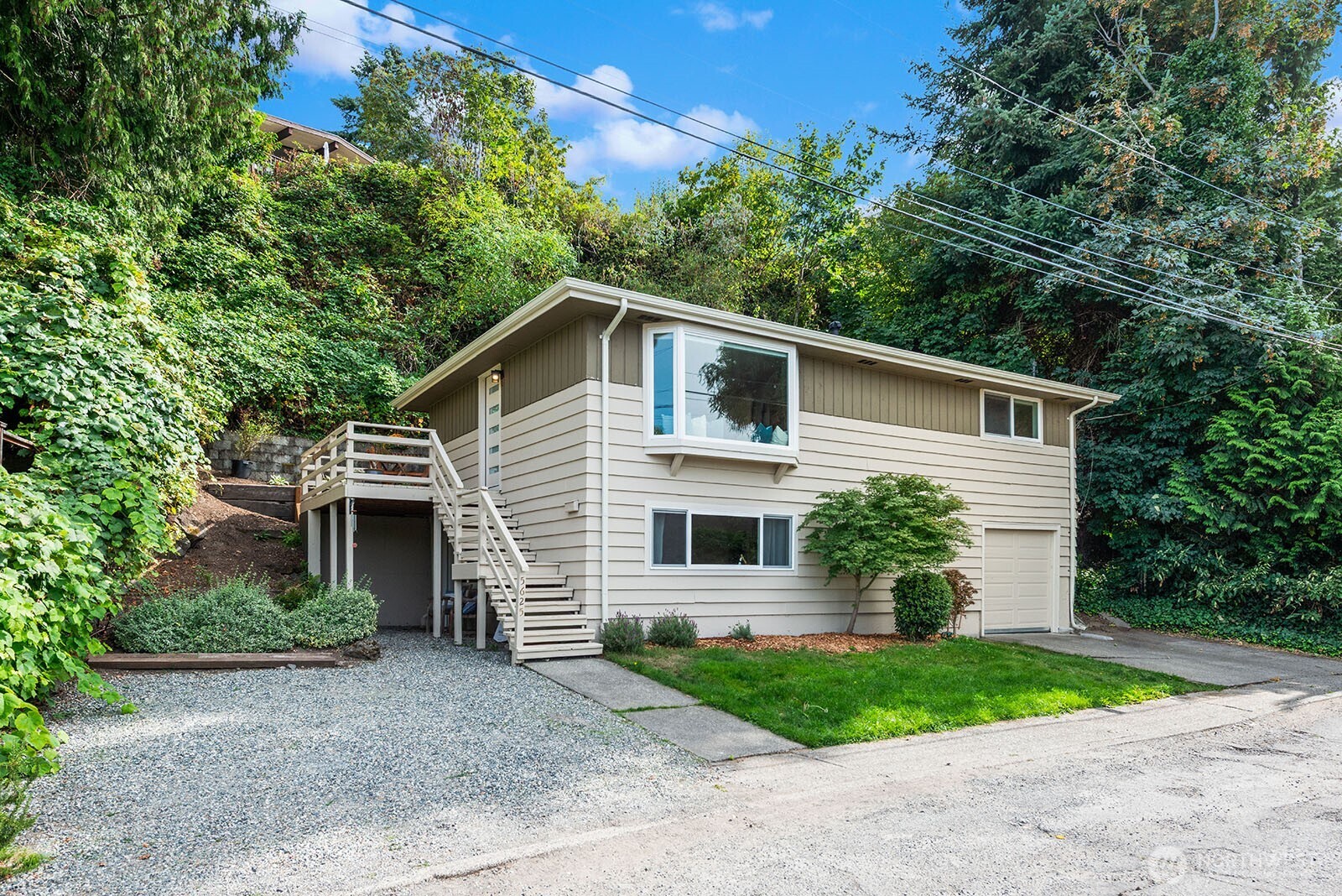 Have you dreamed of living near the beach? On a quiet street just blocks from Alki Beach, this charming residence may be your dream come true. Enjoy privacy, a lovely territorial outlook,views of the Olympic Mountains, excellent condition, abundant natural light, hardwood floors, and beautifully updated kitchen and baths. Enter from the sunny view deck into an open living space featuring oversized windows, great natural light, & a cozy window seat. The dining area comfortably seats six & can expand to accommodate larger gatherings. Open kitchen offers generous cabinet space, stainless-steel appliances, & quartz countertops. Hardwood floors continue into both bedrooms on this level, which share a remodeled full bath. The lower level features a spacious family room with stacked washer and dryer. With full daylight, this space could serve a variety of purposes. The third bedroom & dedicated bath are accessed from the family room. The current owners have used this area as a permitted short-term rental. With separate entrance, it is also ideal for guests, multigen living, or a home office. An attached oversized one-car garage with EV charger is also accessed from the lower level. Additional features include air conditioning; a new roof, insulation, & sewer lining in 2026; & parking for three additional vehicles. Location is exceptional, Alki’s restaurants, arts, parks, and waterfront just minutes away, along with convenient access to shopping and services in the Admiral Junction.