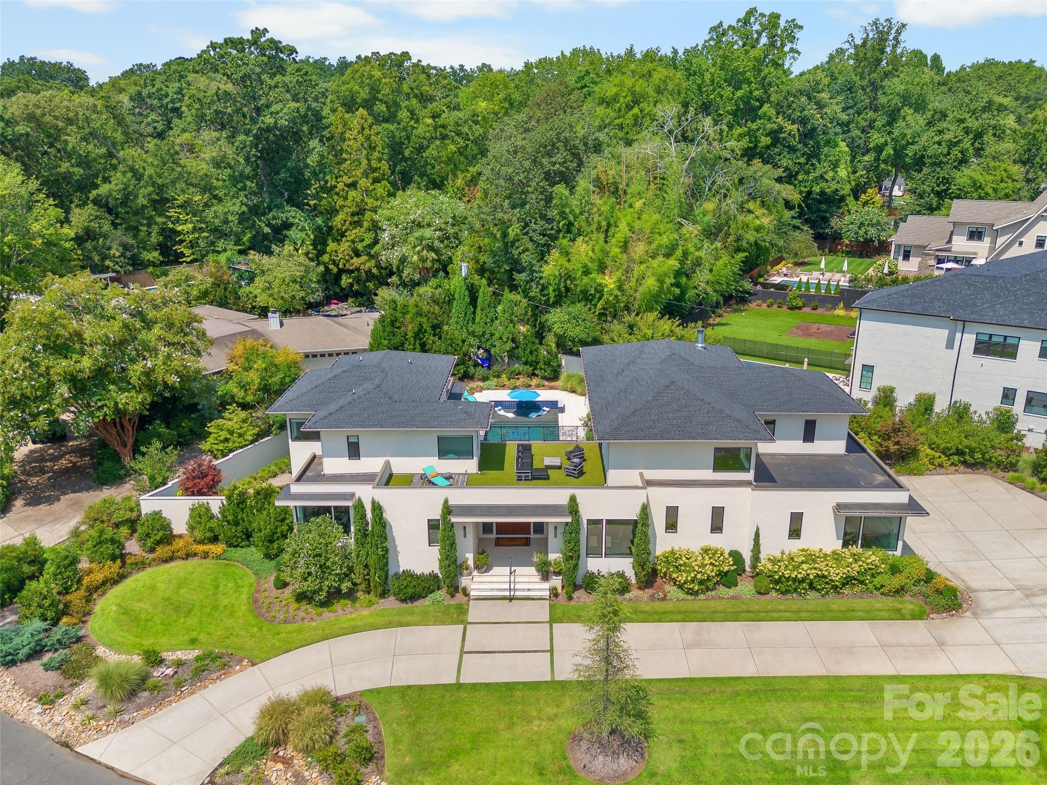 A rare and unique offering in the coveted Mammoth Oaks neighborhood, this exceptional 2022 Custom Luxury Built residence pairs modern architecture with beautifully curated interiors and a resort-inspired private outdoor setting. Spanning more than 5,800 square feet, the five-bedroom, five-and-a-half-bath home is designed for both everyday living and effortless world class entertaining. Endless natural light floods the interior revealing beautiful hardwood floors, luxury lighting, and unique designer finishes, alongside an inviting open floor plan that feels both elevated yet wonderfully livable. At the heart of the home, a beautifully appointed chef’s kitchen features an expansive island with marble that flows seamlessly into the living spaces, and a scullery offering a dedicated workstation. Interior walls offer floor to ceiling walls of windows creating a natural connection to the resort-style outdoor living and views of the pool at every angle. The main-level primary suite offers a serene retreat with a spa-inspired bath, oversized custom closet and laundry room entry.  Four additional bedroom ensuites, an exercise room, a spacious wine cellar/showroom and a tasting room create thoughtfully designed gathering spaces. Outside, a private backyard oasis sets this residence apart. A sparkling pool and spa are framed by an expansive covered patio/grill station and rooftop terrace, creating a spectacular setting for everything from quiet mornings to evenings spent entertaining poolside. Set on a half-acre, the property includes a three car garage, a circular driveway and an enviable location in the heart of South Charlotte: Mammoth Oaks offering a rare blend of privacy and convenience—just minutes from SouthPark, Cotswold, premier dining and shopping, respected private schools, and Uptown Charlotte's business and entertainment district. A true gem that needs to seen in person.
