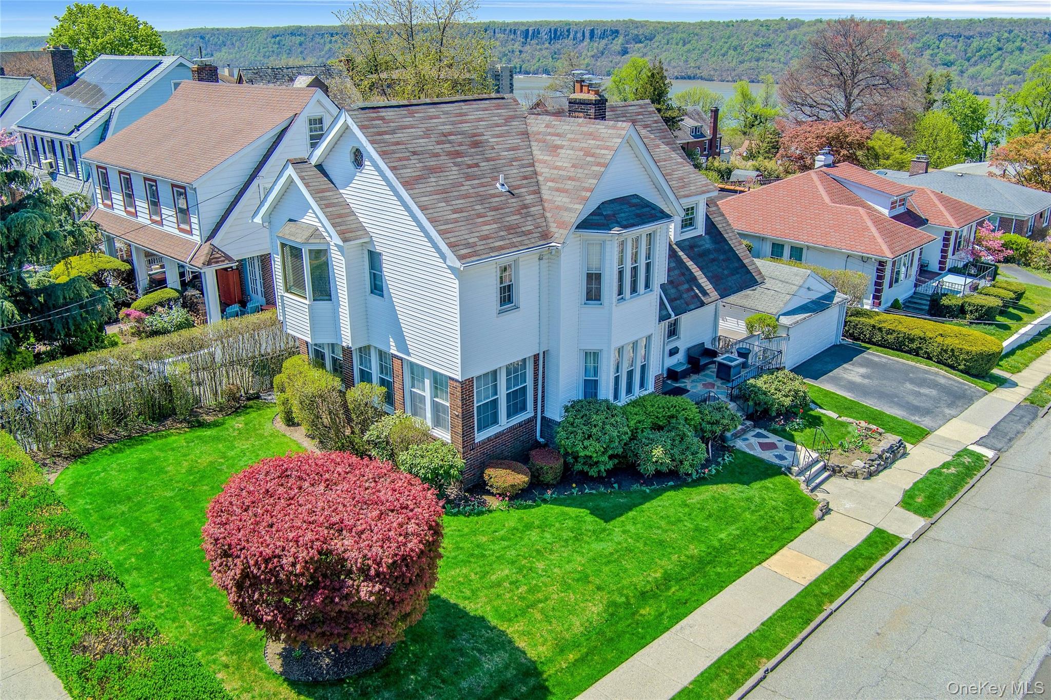 "CORNERSTONE COLONIAL" - Set on a prominent corner parcel in the coveted Woodstock Manor neighborhood, 523 N Broadway is a home that immediately resonates with warmth, character and timeless appeal. Framed by manicured grounds and striking curb presence, this classic Colonial captures the essence of refined suburban living just moments from the Hudson River. From the moment you enter, the home reveals itself through light. Expansive windows line the first floor, flooding each space with natural sunlight and creating an atmosphere that feels both calm and uplifting throughout the day. The living room, anchored by a charming wood-burning fireplace, offers a welcoming place to gather—equally suited for quiet evenings or lively conversation. Just beyond, a series of beautifully proportioned rooms unfold, including a formal dining room wrapped in walls of windows, a sun-drenched den and a versatile home office or playroom—all thoughtfully positioned to overlook the lush, private grounds. The kitchen blends function and flow, with direct access to an outdoor deck ideal for al fresco dining, entertaining or simply enjoying the peaceful setting. The home's connection to the outdoors is seamless, with every angle designed to bring in greenery, light and seasonal beauty. Upstairs, four generously sized bedrooms provide comfortable accommodations, including a primary suite with its own ensuite bath, bonus sitting room and loft—perfect as a private retreat, dressing area or secondary office. Select rooms capture glimpses of the Hudson River, while the front porch offers seasonal river views that serve as a daily reminder of the home's exceptional location. The lower level introduces additional flexibility, with a partially finished walk-out basement ready to be transformed into a media room, recreation space, gym or entertaining lounge. Completing the offering is a rare detached garage, an increasingly hard-to-find feature that adds both convenience and long-term value. Positioned just seconds from the Hudson River waterfront, this home places you at the center of one of Yonkers' most desirable and evolving areas. Enjoy close proximity to Old Croton Aqueduct Trail, Hudson River Museum, Lenoir Preserve, Untermyer Gardens, the Yonkers waterfront promenade and a growing collection of local cafes, restaurants and shops. Commuting is effortless with nearby Metro-North stations offering a seamless ride into Manhattan in approximately 30 minutes, along with easy access to major parkways and roadways. Discover Westchester's vibrant river towns such Hastings, Dobbs Ferry, Irvington and Tarrytown just minutes away. This is more than a home—it's a setting, a feeling and a lifestyle. A place where classic architecture meets everyday comfort, where light fills every corner, and where the rhythm of the Hudson is always just moments away...