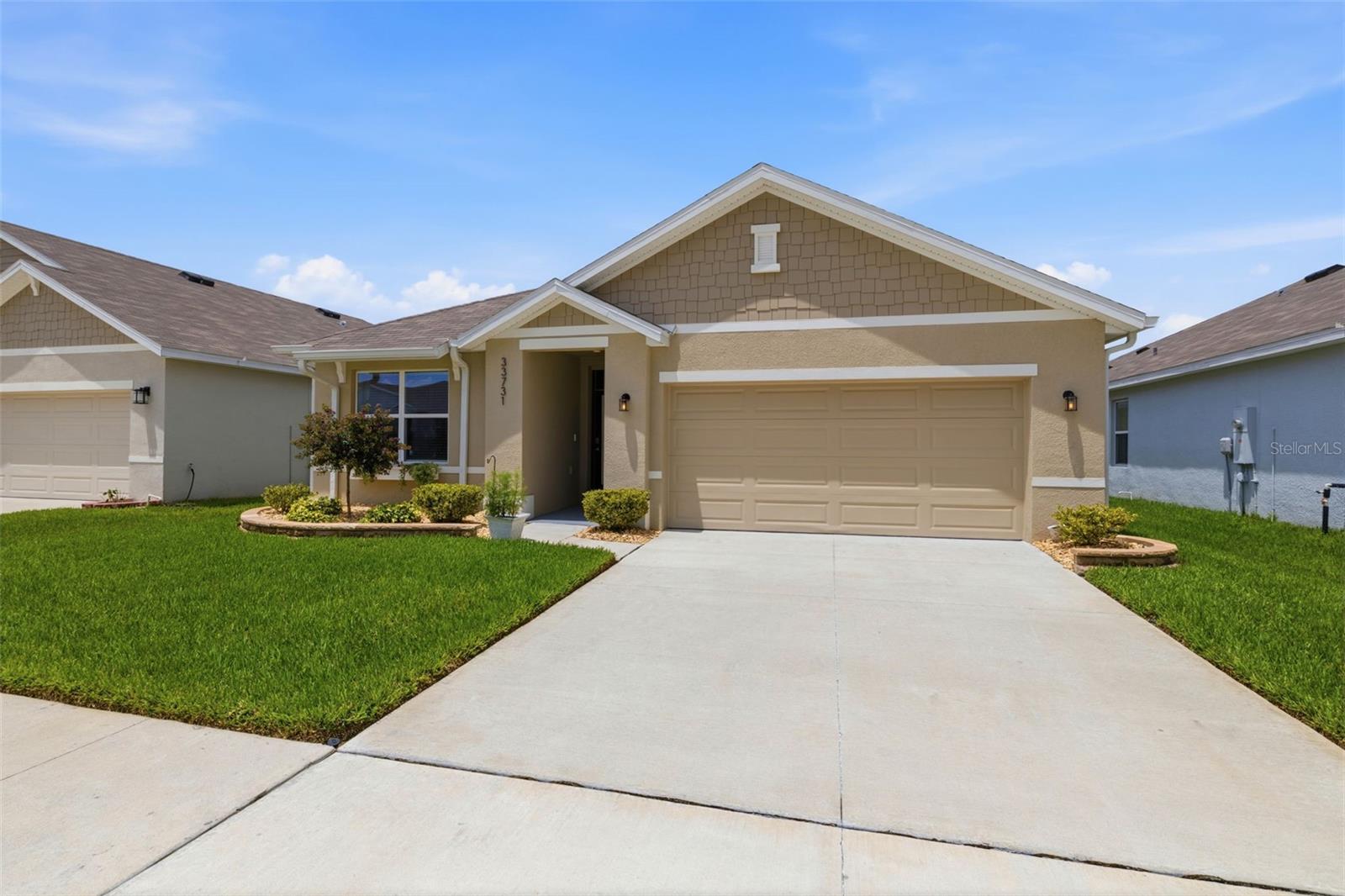 Welcome to this beautifully upgraded 2024 DR Horton home in the sought-after Avalon Park West Community of Wesley Chapel! This move-in ready one-story residence offers 1,690 square feet of thoughtfully designed living space with 3 bedrooms, 2 bathrooms, and an open-concept floor plan perfect for everyday living and entertaining. From the moment you arrive, you'll appreciate the exceptional curb appeal featuring lush professional landscaping, flower beds, elegant paver stone landscape boarders, decorative rock landscaping, three crepe myrtles, knockout roses that bloom throughout multiple seasons, upgraded St. Augustine sod, exterior gutters, and added rear irrigation. The inviting front entry showcases an impact-resistant glass insert with built-in blinds, transom window, invisible retractable screen, and Kwikset keyless entry. Inside, you'll find fresh interior paint, tile flooring throughout the main living areas, luxury vinyl plank flooring in the third bedroom, recessed lighting, updated light fixtures, ceiling fans, marble window sills, and an abundance of natural light through double-pane windows. The spacious kitchen is a showstopper with quartz countertops, subway tile backsplash, a large island with stone-accented front, single-basin sink, upgraded faucet, Whirlpool stainless steel appliances, a generous pantry, and a convenient spice rack. The primary suite offers a large walk-in closet and an upgraded ensuite bath featuring quartz countertops, an updated spacious shower with glass enclosure, dual sink vanity and a luxurious rain shower head. The guest bathroom includes a quartz counter top vanity and ample storage. Additional upgrades include a Culligan water softener, whole-house surge protector, alarm system, garage door opener, PVC privacy fencing, screened lanai with ceiling fan, creating the perfect outdoor space to relax or entertain. Enjoy all that Avalon Park West has to offer, including outstanding community amenities, pools, parks, walking trails, and convenient access to shopping, dining, schools, hospitals, and major highways. 100% USDA financing is available (eligibility confirmed for this address), and no flood insurance is required.  This better-than-new home is loaded with upgrades and ready for its next owner. Schedule your private showing today!