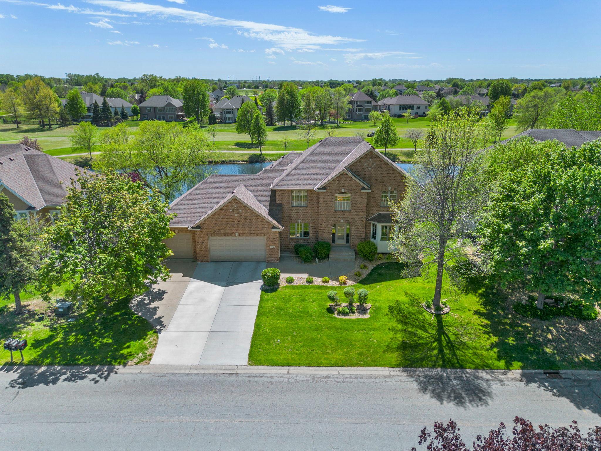 Welcome to this stunning 5-bedroom, 4-bath home in the highly sought-after Deacon’s Walk community in Blaine, perfectly positioned with backyard views of the 3rd fairway at TPC Twin Cities and a scenic pond. Ideally located near Palmer Park, walking paths, shopping, and dining, this home offers an exceptional blend of convenience and lifestyle. A grand foyer with 18-foot ceilings, hardwood floors, and a statement chandelier sets the tone for the open, light-filled main level. The kitchen features abundant wood cabinetry, granite countertops, a center island with breakfast bar seating, stainless steel appliances, and flows into the informal dining area with access to a maintenance-free deck overlooking golf course and water views. Multiple living spaces include a formal dining room, a front living room, and a cozy family room with a stone gas fireplace, built-ins, and large windows. The main level also includes a laundry room, half bath, and heated, insulated 3-car garage with attic access. Upstairs, four bedrooms include a spacious primary suite with a large walk-in closet and spa-like ensuite featuring a jetted tub, walk-in tile shower, and dual vanity. Three additional bedrooms share a full bath with updated finishes. The walkout lower level offers a family and recreation space with recessed lighting, a wet bar, and direct access to an expansive patio. A lower-level bedroom with walk-in closet and nearby ¾ bath adds flexibility for guests or office space. The backyard is a true highlight, offering panoramic golf course and pond views with a lush lawn and in-ground irrigation system. Updates include siding (2024), furnace (2022), water heater (2021), concrete driveway (2021), and roof (2017). A rare opportunity in a premier location.