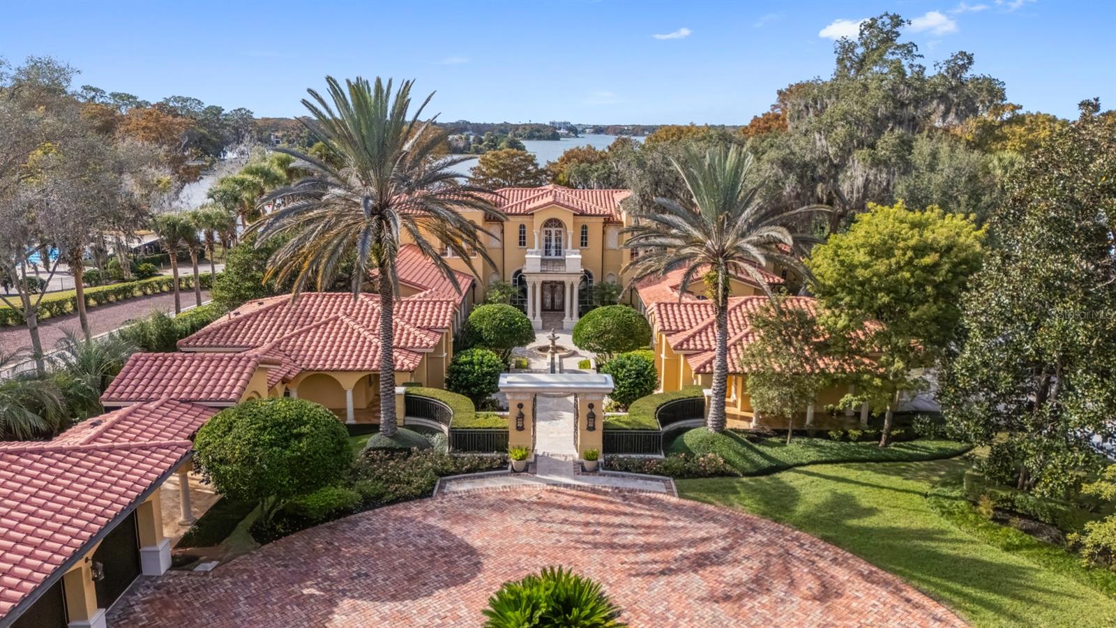 Under contract-accepting backup offers. Elegant Mediterranean estate, masterfully crafted by Akers Custom Homes and set within the heart of the Vias. Privately tucked behind a gated drive, the approach unfolds to a grand circular motor court framed by lush, manicured grounds spanning over two acres with impressive sunset views across Lake Maitland. Every element of the estate is thoughtfully connected by covered walkways, including five garages (three-car and two-car) and two motor courts, a detached office or seventh bedroom suite, and a lakeside pool cabana, creating a seamless blend of function, elegance and architectural harmony in this one-owner Lake Maitland residence. A dramatic arrival sets the tone as a flowing water feature guides guests along the walkway to the front entry. Inside, the grand foyer opens to a breathtaking gathering room, anchored by soaring two-story windows that frame panoramic lake views, the expansive terrace and terraced outdoor space. A dedicated space for a grand piano enhances the home’s capacity for elegant entertainment and memorable gatherings. The spacious kitchen overlooks the family room and is positioned alongside a dedicated bar, breakfast room and dining room. The family room, warmed by a gas fireplace, is filled with natural light and opens through a wall of French doors to the open terrace, blurring the line between indoor and outdoor living. The first-floor primary suite is a serene retreat with French doors to a covered outdoor space, a fireside sitting area wrapped in custom bookshelves, and a spa-inspired bath featuring a large glass shower, soaking tub, expansive walk-in closet, and a versatile flex room ideal for yoga, massage or expanded wardrobe space. A full guest suite with en-suite bath and walk-in closet is also on the main level. Upstairs, a grand mezzanine overlooks the gathering room, offering a dramatic extension of the living areas. French doors open to a front balcony, while the west wing features two bedrooms with a shared private living room and full bath. The east wing hosts two additional bedroom suites, each with walk-in closets and en-suite baths, one enhanced by a private sitting area and access to a spacious rear balcony. Off the kitchen, a wrought-iron gate leads to the basement level, where a refrigerated wine cellar, theater room, and generous storage space await. Outdoors, the stunning terrace showcases a heated spa, sparkling lakeside pool, expansive gas fire pit and an extraordinary 700-square-foot pool cabana that offers a wraparound screened porch with summer kitchen, a full bar, gaming area and full bath, ideal for lakeside entertaining. Elevated above the water for commanding views and shielded from the main road for complete privacy, this remarkable estate is a masterpiece, designed for multi-generational living and destined to create lasting memories for generations to come.