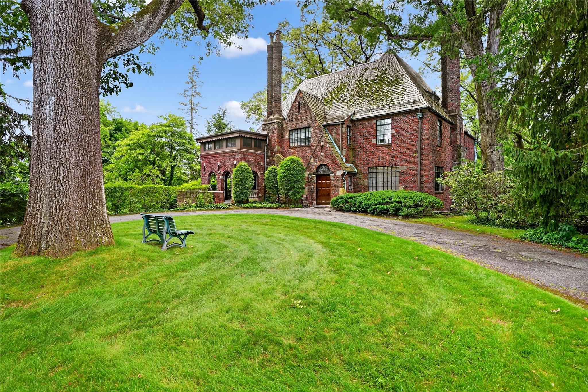 Step back in time to the Jazz Age with this exquisite vintage 1920’s Tudor, ideally situated on a sprawling, verdant lot. This 5 bedroom residence proudly preserves a wealth of original details, offering a glimpse into a bygone era of elegance.

Entertain in the grand living room, where a magnificent wood-burning fireplace with a hand-carved mantle invites intimate gatherings and a charming book nook promises quiet contemplation. Leaded glass windows cast a soft glow, and French doors open onto a stone-covered patio, a masterpiece of arches and intricate brickwork, perfect for al fresco soirees. Adjacent, the sunroom, with its wide plank floors and sliding glass door, leads to a wooden deck overlooking an expansive yard, complete with a dance patio for lively evenings.

The formal dining room, ideal for grand dinner parties, flows seamlessly into a butler's pantry. The kitchen is equipped for modern convenience with an electric range, dishwasher, and double wall ovens. A laundry room is conveniently located off the kitchen, alongside a charming breakfast room and a powder room.

Ascend to the second level, with 4 bedrooms and 2 full bathrooms. The first large bathroom has two sinks, a tub/shower, and an additional shower.  The second full bathroom has a bathtub/shower and linen closet. The king-size primary bedroom is a true sanctuary, featuring an en suite bathroom, ample closet space, and an en suite office + sleeping porch adorned with detailed brickwork – a private retreat for the discerning owner. A dedicated back staircase from the kitchen leads to a sitting room/lounge.

The walk-up third floor offers a versatile space, perfect for a lively hang-out area, an additional private office, and abundant unfinished storage & cedar closet.

The lower level provides a spacious recreation room, extensive storage solutions, a half bathroom, and an oversized two-car garage, completing this unparalleled offering of Gatsby-era charm and modern comfort.

Easy walk to school, train and Hartsdale. Come live the life!