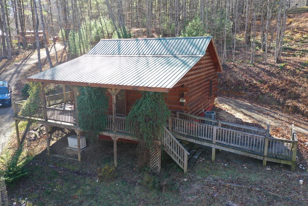 Secluded log cabin nestled in a wooded setting, yet conveniently located just minutes from everyday amenities. This 2-bedroom, 1-bath retreat offers an open-concept living room and kitchen with vaulted ceilings and hardwood floors throughout. A gas-log fireplace provides a warm focal point, while the 280 sq ft covered deck offers the perfect place to relax and enjoy the surrounding mountain breezes.  A small creek runs through the property, which also features a small pond, storage shed, and detached carport. Wildlife is frequently observed in the area. The location provides easy access to Exit 8 and Exit 14 off Interstate 77 and is approximately 5 miles from the Blue Ridge Parkway, Crooked Creek Wildlife Area, and the Blue Ridge Music Center.