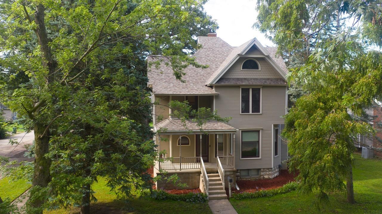 Stunning 1900s home on Charles City’s west side featuring significant improvements that provide modern amenities while preserving the home’s original craftsmanship, character and history. Enter from the covered front porch through the original front door, where decorative glass boldly displays the original builder’s “G.P.S.” initials – George P. Smith. Inside the foyer, a beautifully refinished quarter-sawn oak staircase immediately draws your attention. Hardwood flooring continues throughout the main level, with the dining room showcasing a distinctive period contrasting inlay border. Extensive one-of-a-kind custom fabrication by Amish woodworkers includes a built-in bookcases, drawers and storage surrounding a decorative architectural fireplace centerpiece. The functional kitchen features floor-to-ceiling raised-panel oak cabinetry, stainless-steel appliance package and convenient half bath nearby. The upper level offers three bedrooms and a full bathroom, along with a rear staircase providing direct access to the kitchen. The basement features unusually tall ceilings, laundry area and a dedicated workshop equipped with multiple 240V circuits for larger equipment. Exterior amenities include a fully insulated two-stall detached garage with LG wall-mounted air conditioner and multi-speaker surround system. Enjoy the patio with motorized retractable awning and remote control, plus a semi-private fenced yard enhanced by mature trees and established landscaping. A distinctive home where historic character, craftsmanship and thoughtful improvements come together – and it’s ready for you to move right in!