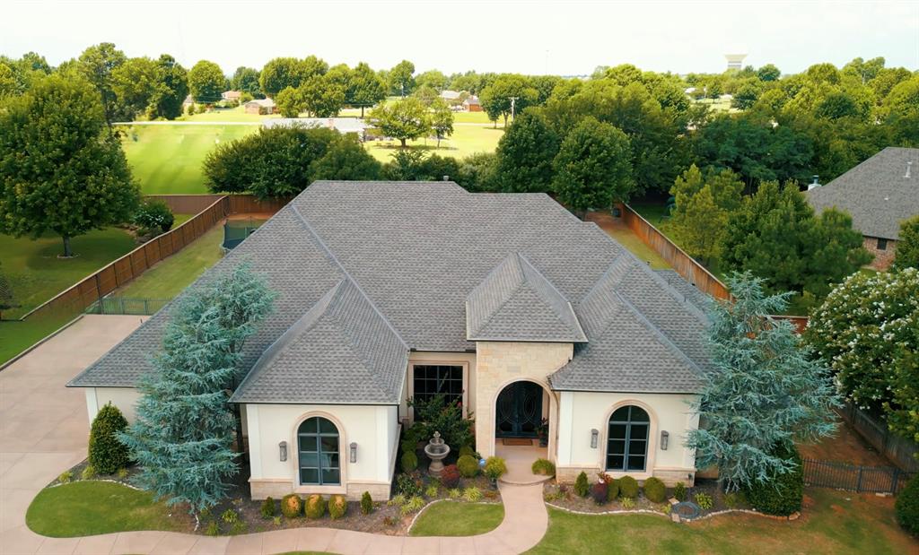 This one-of-a-kind, custom built home, is a standout in north Edmond. As you pull into the gated neighborhood and drive the tree-lined streets, you arrive at the beautiful Stagmoor estate. The manicured yard, large windows and modern elevation are show stoppers. The lot boasts over 3/4 acre and is one of the biggest in the neighborhood. Step through the custom iron front doors into the openess of the main living space. Invite the friends & family over as the dedicated formal dining space is large enough for a crowd and is open to the mail living area. Gather around the fireplace to enjoy time together while entertaining in the kitchen and large wrap-around bar area. The chef's kitchen is specially designed with all the bells and whistles, including granite countertops, custom vent hood, plenty of storage and a walk in pantry that doubles as a safe room. The eat-in kitchen area is perfect for those more intimate family dinners. The built-in office space is tucked away, out of site, and is perfect for keeping the household organized. The extra living space is one of a kind with surround sound, projector hook up, and ready for the next movie night. The spacious primary bedroom faces the backyard and is perfectly paired with the en-suite bathroom. Each vanity has its own space and a featured accent wall for the bathtub and walk around shower. Both secondary bedrooms have their own full bathroom and are spread out giving each area its own privacy. As you step out onto the back patio, the view is amazing with its own retreat. The covered back area has a built-in grill, surround sound, bar top and is ready for a pool party. The large pool is ready for the summer with a built in slide and diving board. Another covered area gives plenty of room for guests to be in the shade. A large grassy area is perfect for volleyball, trampoline and for the kids and dog to run around. Don't miss out on this one of a kind, before it's gone!