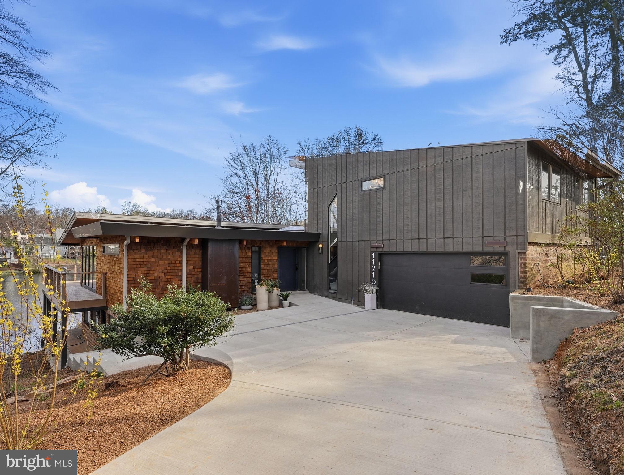 11216 S. Shore Rd Reston VA  ** On Lake Anne **A 6 bedroom 5 1/2 bath, modern lakefront home built for the way you actually want to live.From the moment you  step onto the main level, Lake Anne stretches out before you wall to wall.  The sunsets here will rearrange your evening plans.  The light drops into the water and paints everything gold.This is an original mid-century home on one of Lake Anne's most coveted waterfront parcels, comprehensively reconstructed from the inside out. The renovation substantially expanded the upper level footprint, introduced a fully finished lower level, and replaced every mechanical, plumbing, and electrical system in the house.  The setting and architectural bones are Lake Anne.  Everything else is new.** Main Level **Open-plan living organized around uninterrupted water views, expressed through expansive glazing and a fluid layout designed for gathering.  The kitchen anchors the space with a commercial-grade dual-fuel 48" range, industrial-sized vent hood with external blower, extra-large workstation sink, walk-in pantry, and an oversized island built for prep and seating.  Custom maple cabinetry, quartzite and quartz counters, well-designed task lighting, and hidden outlets throughout.  A gas fireplace warms the living area, while a wraparound Timber-Tech composite deck extends the footprint outdoors through three 10' sliding doors.  This level also includes a main-level ensuite bedroom, a dedicated laundry room with utility sink and built-in cabinetry, and a half bath.** Upper Level **The primary suite is the showpiece:  floor-to-ceiling glass spanning the full width of the lake.  Step directly onto a private terrace for morning coffee or an evening drink with nothing but water and sky.  The suite includes a walk-in closet and a spa-caliber bath with soaking tub, separate double shower, and heated floors.  Two additional bedrooms share a second full bath finished with cohesive designer selections.** Lower Level **A fully self-contained residence with its own exterior entrance onto a covered lakeside porch.  Two generously scaled bedrooms, each with a private full bath.  Full kitchen with premium full-sized appliances and counter seating.  Dedicated side-by-side laundry.  Living and dining areas centered around a second gas fireplace.  This level functions as a true second home within the home.** Systems & Infrastructure **Comprehensive modernized:  three independent heat pump zones, 400-amp panel with Level 2EV charging port,  duel water heaters (tanked and tankless).  Architectural lighting design and fixtures in all spaces.  The exterior features a maintenance-free standing seam metal roof, pre-dipped cedar shingle siding, triple-paned custom windows, and custom low-voltage landscape lighting.** On the Water **A private floating dock is included, equipped with an electric motor for cruising the lake, with direct access to the water and trails from one of Reston's most architecturally significant lakefront communities.