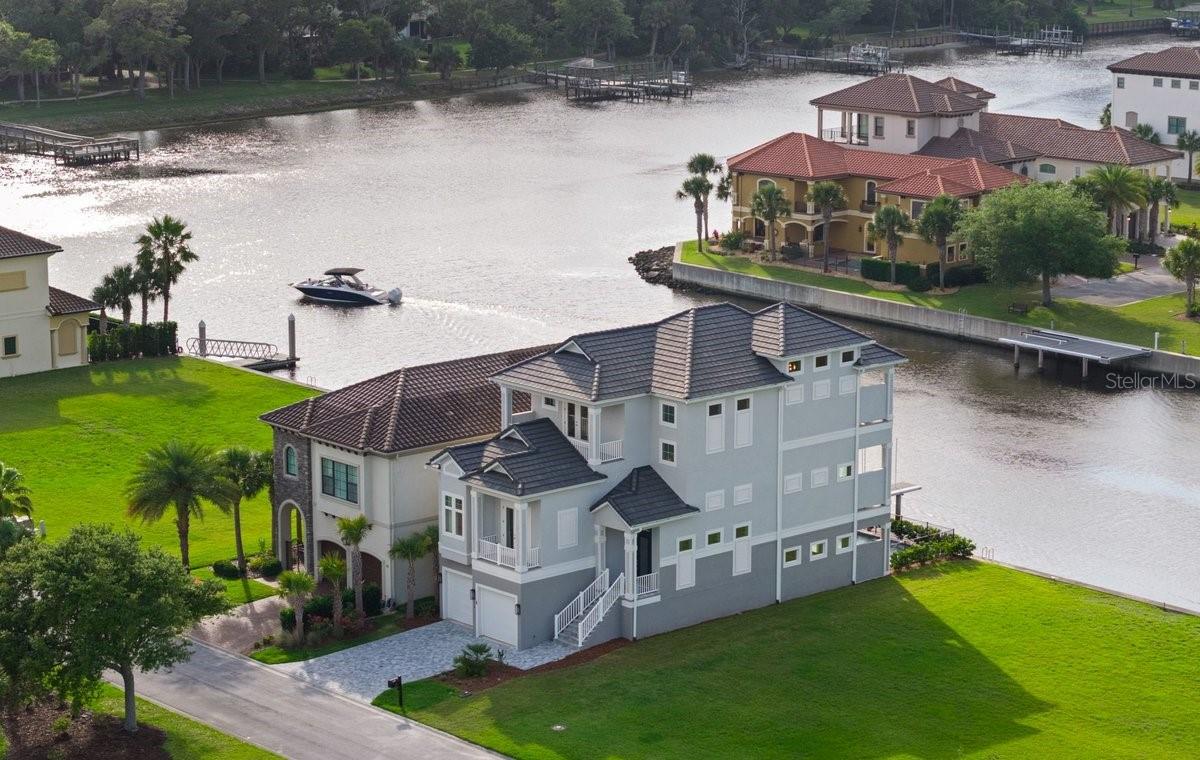 Some homes are beautiful.Others completely redefine the way you want to live.Tucked within the exclusive waterfront community of Yacht Harbor Village along the Intracoastal Waterway in the Hammock of Palm Coast, this custom-built residence was designed for those who refuse to compromise between boating, beach days, golf, and refined coastal living… because here, you truly can have it all.From the moment you step inside, the home feels effortlessly sophisticated yet warmly inviting. Soaring ceilings, dramatic designer lighting, expansive walls of glass, and carefully curated finishes create a timeless coastal aesthetic that feels elevated without ever feeling overdone. Thoughtfully designed for both everyday living and unforgettable entertaining, the open-concept spaces flow seamlessly from indoors to out.At the heart of the home, the chef’s kitchen is both functional and stunning, featuring custom cabinetry, oversized island seating, premium appliances and finishes, and a waterfront dining space perfectly positioned to capture the peaceful water views beyond. A private first-floor retreat complete with its own kitchen/bar area and ensuite bath offers exceptional flexibility for guests, multigenerational living, or elevated entertaining.Designed with comfort and convenience in mind, the home also features a private elevator servicing every level, dual laundry rooms, spacious guest ensuites, and an extraordinary primary suite that feels reminiscent of a private luxury resort. Complete with its own balcony overlooking the water, a spa-inspired bath, soaking tub, oversized walk-in shower, and designer finishes throughout, the space was created as a true retreat from everyday life.Outside, your own private waterfront oasis awaits. Wide canal views, direct Intracoastal access, a sparkling pool, expansive outdoor living spaces, and breathtaking evening skies create an atmosphere where every day feels like a vacation.With Yacht Harbor Marina located within the community, beach access just minutes away, and optional membership opportunities available through Hammock Dunes Club and Hammock Beach Resort, this offering is far more than simply a home.It’s the coastal lifestyle people spend years dreaming about… and very few ever truly find.