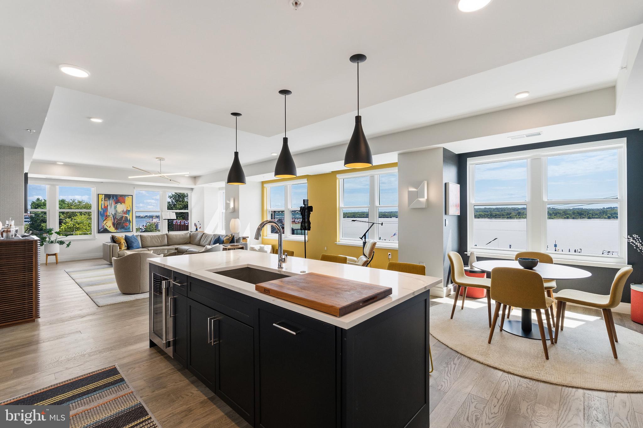 Experience luxury waterfront living in this beautifully curated 2,800-square-foot residence at Watermark, one of Old Town Alexandria's premier condominium communities. Thoughtfully designed with the guidance of an interior designer, this rarely available three-bedroom, three-bath home offers Potomac River views from every room and refined finishes throughout. Wide-plank hardwood floors, 9-foot ceilings, custom millwork, designer lighting, Italian cabinetry, quartz countertops, and premium stainless steel appliances create an elegant yet comfortable living environment.A welcoming foyer with custom built-ins and accent lighting leads to the sophisticated living spaces. The open living room is framed by large windows showcasing panoramic views of the Potomac, Old Town waterfront, National Harbor, and Washington, D.C. The space centers around a gas fireplace, creating a warm gathering space while boats cruise by outside. The chef's kitchen pairs sleek Italian cabinetry with quartz countertops, designer tile backsplash, and Thermador appliances. A large island invites casual dining, while the adjacent eating area provides the perfect setting for everyday dining. The separate formal dining room, overlooking Old Town and the Potomac, is equally suited for entertaining or more intimate affairs.The primary suite is a true sanctuary, complete with a spa-inspired bath, two walk-in closets, separate shoe closet, and dedicated dressing area. A generous second bedroom offers its own en-suite bath, custom walk-in closet, river views, and direct access to the private terrace. The third bedroom, currently used as a home office, features French door with frosted glass, two closets, and terrace access.Additional highlights include custom shades throughout, designer lighting, a whole-home water filtration system, a private storage closet conveniently located just outside the residence, and two assigned garage parking spaces.Watermark amenities include an elegantly appointed lobby, secure fob-controlled elevator access, bike storage, and a spectacular rooftop terrace with grilling stations, a fire pit, and sweeping views of the Potomac River and the U.S. Capitol.Perfectly positioned in the heart of historic Old Town, you're just steps from acclaimed restaurants, boutique shopping, the waterfront, parks, trails, and the vibrant charm that has consistently earned Alexandria national recognition as one of America’s best small cities. With comparatively low condominium fees and the option to purchase the home fully furnished, this is a rare opportunity to enjoy turnkey luxury in an unmatched waterfront setting.