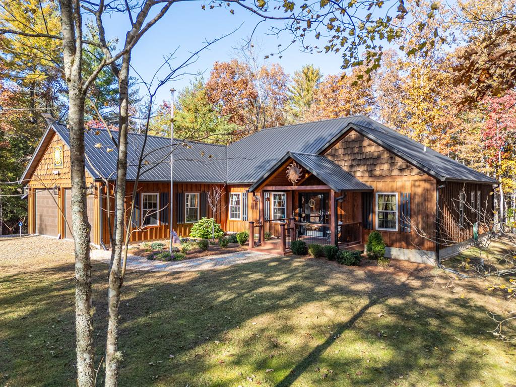 This beautifully crafted 3-bedroom, 2.5-bath cabin, built in 2021, sits on 5.16 private wooded acres just minutes from downtown Murphy, NC, and Blue Ridge, GA.    Step inside to a warm and inviting open-concept great room featuring an all-wood interior, soaring vaulted ceilings with exposed beams, and a striking stone fireplace—the perfect setting for cozy mountain evenings.    Enjoy one-level living with a split floor plan that offers both comfort and privacy.   The primary suite is a true retreat, complete with its own fireplace, a luxurious private bath, and a spacious walk-in closet.  Two additional bedrooms plus a separate office or den provides flexible living space for family, guests, or remote work.   The oversized kitchen and dining area are made for gathering, showcasing custom cabinetry, granite countertops, a massive island with seating, a built-in desk, and a well-lit walk-in pantry.  Thoughtful details continue throughout with utility and storage closets, along with a convenient laundry area.   Outdoor living shines here—relax or entertain year-round on the expansive screened porch with a gas fireplace.   The property also offers a designated RV parking area with 30-amp power, water, and dump station, plus an oversized double garage.   A rare combination of craftsmanship, space, and functionality—all tucked into a peaceful, wooded setting.   Whether you're seeking a full-time residence, vacation escape, or short-term rental investment, this home checks every box.  Modern construction, quality finishes, and serene surroundings deliver mountain living at its finest.