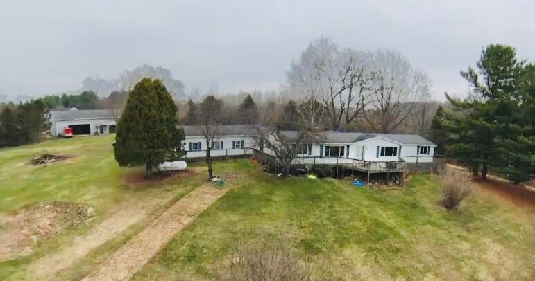 Nestled on just under Ten Acres, this Desirable Ranch-Style Home is Anchored by an Expansive Pond, which Features around 340Ft. of Water Frontage, and Breathtaking Views. Encompassed by a Full Wrap-Around Deck, the Outdoor Entertainment Possibilities are Endless. Upon Entering, You are Greeted by a Large Mudroom, Attached to another Spacious Mudroom/Storage Area. A Gorgeous Stone, Wood-Burning Fireplace Highlights the Alluring Open Floor Plan, which Ties Together the Vast Kitchen/Dining/Living Areas. Stunning Knotty Pine Beckons Throughout, while Leading You into the Bright Sunroom~ which Features Admirable Cathedral Ceilings. The Main Floor is also Home to The Primary Bedroom which is Accompanied by a Private Full Bathroom; along with a Second Bedroom, and another Full Bathroom. Winding Downstairs, You will Find an Expansive Family Room, along with Four More Convenient Bedrooms. There is also an Additional Finished10x12 Bonus Room, along with a Vast Amount of Storage Space.Wandering back Outside~ the Spacious Three-Stall Attached Garage, Brings it All Together. This Property also Highlights an Insulated 40x80 Pole Barn, which features a Convenient Pit, and 14Ft. Eaves~ So Many Possibilities Here! To Top it Off for any Hunters, there is an Existing Hunting Blind that Stays with the Property. *New laminate flooring inside (2025). Furnace and A/C- 5 yrs. old +/-. Replacement windows (2016)