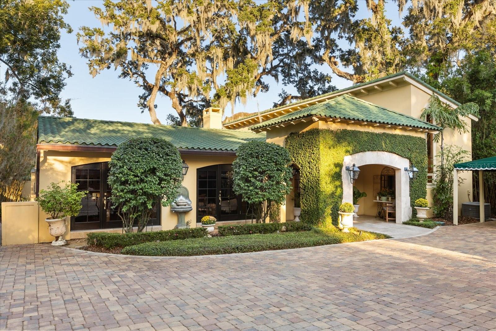This beautiful Mediterranean style home offers a rare opportunity for prime waterfront living on Lake Mizell, part of the highly sought out after Winter Park Chain of Lakes. The property is just a short walk or drive to Park Avenue’s restaurants, boutiques, and local attractions. The main home features three bedrooms and five bathrooms, each bedroom offering its own en suite bathroom. A separate guest house (ADU) provides an additional 932 square feet with two bedrooms, one bathroom, newly refinished original hardwood floors, fresh paint and a wood burning fireplace perfect for guests or extended family. Inside the main residence, you’ll find solid wood and travertine flooring throughout the first floor, surround sound speakers, a wood burning fireplace and freshly painted interiors. The living room features large windows overlooking the lake, with an open floor plan that flows seamlessly into the dining room and kitchen. The gourmet kitchen showcases a beamed ceiling, Busby custom three tone cabinetry with granite countertops, a six burner gas cooktop, and a built in ice maker. The dining area offers easy access to the outdoor entertaining spaces, perfect for enjoying lakeside gatherings. The primary suite occupies the entire second level, offering dual bathrooms, individual walk in closets, and a private balcony with unobstructed lake views. Additional features include an inviting office/den with french doors and custom built ins, as well as a spacious laundry room with ample cabinetry, a 120 bottle wine fridge, and a secondary refrigerator for added convenience. An expansive paver driveway leads to covered parking that accommodates up to three vehicles. Traditional gas lanterns and built in landscape lighting enhance the home’s Mediterranean charm and highlight its mature, manicured grounds. Outdoor living is the centerpiece of this property, featuring durable composite board decking, a summer kitchen with an infrared grill, and a hot tub for relaxing and entertaining. Enjoy multiple inviting seating areas with stunning east facing lake views. The private boat dock includes a storage closet, boat lift, and the boat itself is included. This home offers relaxed luxury and timeless lakefront living in one of Winter Park’s most desirable neighborhoods.