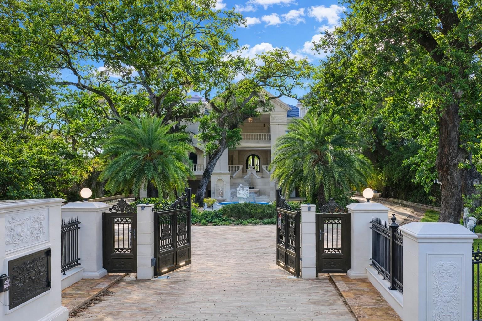 Palazzo Sul Mare is a rare waterfront estate in St. Petersburg’s coveted Jungle Prada neighborhood, offering over 19,000 square feet under roof and more than 10,000 square feet of interior living space on over 1.5 acres along the Intracoastal Waterway. Built in 2020, this residence blends modern construction with timeless European-inspired design—an offering rarely found in this market.A grand motor court and porte-cochère create a secure, estate-style arrival. An imported limestone exterior, along with wrought iron detailing, a distinctive blue dome, fountain, marble statuary, and mature oak trees, establishes a timeless setting surrounded by tropical landscaping and the neighborhood’s iconic peacocks. Inside, a dramatic domed rotunda crowned by a crystal chandelier anchors the home, featuring inlaid marble flooring and dual sweeping marble staircases. The layout captures water views throughout, with a gallery-style corridor ideal for art, a grand piano, or entertaining. Marble archways and columns, gold and iron balustrades, and detailed ceilings create a striking architectural presence, while illuminated art niches enhance the home’s scale and design continuity.Custom millwork, fresco-style ceilings, and imported marble flooring span all three levels. The kitchen features a full suite of Thermador appliances, including a 60-inch gas range, integrated refrigeration, and built-in coffee system, along with quartzite surfaces and an illuminated onyx island. A custom Chihuly-style installation of hand-blown glass creates a focal point above, while the curved glass dining area frames panoramic water and pool views with space for large-scale entertaining.The residence includes multiple bedroom suites, several exceeding 1,000 square feet, many with spa baths, expansive closets, and private lanais with water or garden views. The main-level primary suite offers a marble bath with Phylrich fixtures, sauna, soaking tub, multiple vanities, and panoramic water views beneath a custom fresco ceiling.A private office on the main level features paneled walls, built-ins, an ornate stone fireplace, and balcony access. The upper level includes a club-style lounge with a quartzite waterfall bar and sunset views. The home spans three levels with elevator access and marble staircases, with laundry rooms on multiple levels.Outdoor living includes a zero-entry pool, lap pool, 2 spas (hot and possible cold), 5 terraces, courtyards, fire pit, private sandy beach, citrus trees, and a wide rear lawn. The grounds offer flexibility for a guest house or ADU, sport court, cabana, or greenhouse. The private dock includes a 10,000-lb lift, additional lifts for personal watercraft, a wet slip for a yacht, and direct Gulf access.Built for longevity with reinforced pier-and-beam construction on pilings, impact-rated windows and doors, and a stone exterior. Designed with engineered elevation, the residence features elevated living areas (approx. 7.7’ first level and 20’+ upper levels), with no reported water intrusion. Smart home technology, full security camera coverage, solar power, saving thousands per month in electricity, 4 HVAC systems (2023) with 10-year warranties, and 2 whole-house generators for efficiency and reliability.Garage capacity for approximately 6 vehicles includes additional space for a workshop, recreation, or gym with over 5,000 square feet of lower-level space. A rare combination of scale, craftsmanship, and waterfront presence.