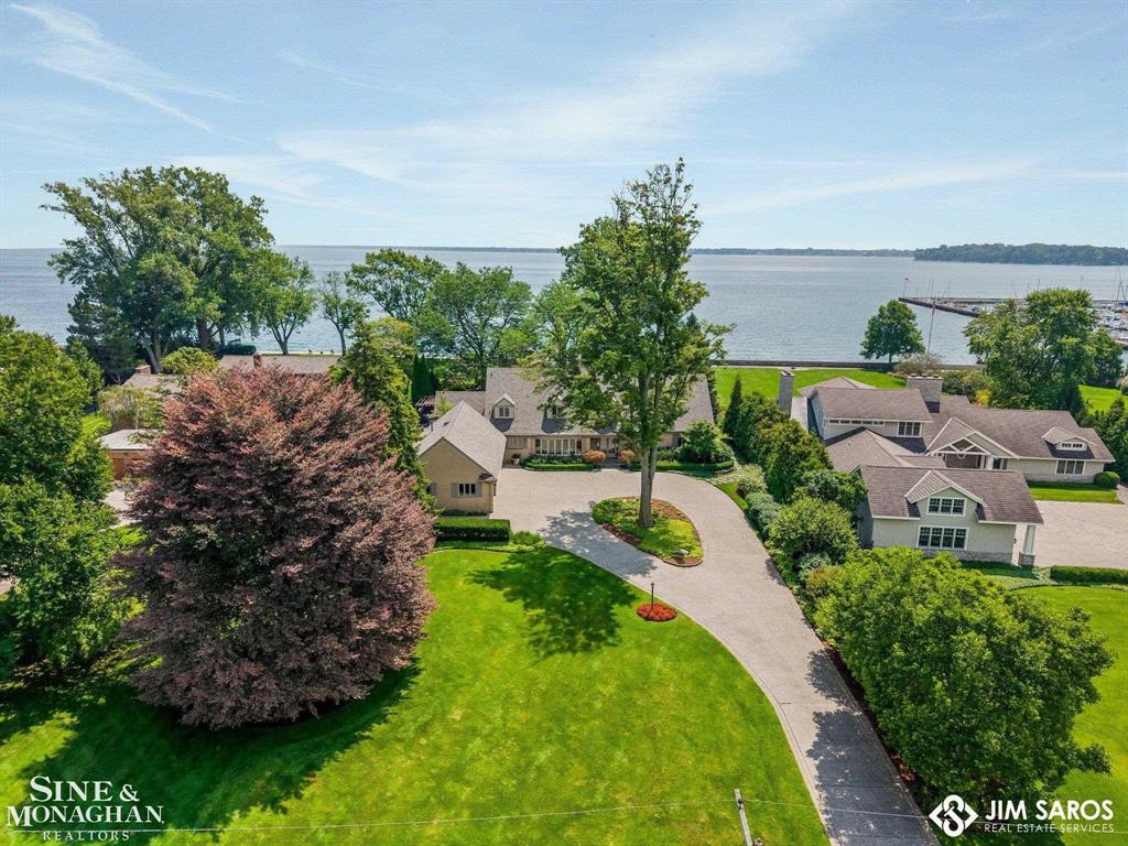 Lake St. Clair is your backyard at this extraordinary waterfront residence, boasting 135 feet of private frontage with sweeping views, breathtaking sunrises, and freighters gliding past as part of the daily rhythm of life. Here, the lake isn't just a view-it's a lifestyle of serenity, recreation, and beauty. The grounds are a true sanctuary, featuring multiple koi ponds, trickling streams, and thoughtfully designed gardens bursting with color. A generous bluestone patio stretches toward the water, offering the perfect setting for entertaining, relaxing, or simply soaking in the unmatched lakefront atmosphere. Inside, this home offers the rare luxury of dual primary suites-one on the main floor and one upstairs-each with panoramic lake views and spa-like en suites. Nearly every room captures the water, blending indoor comfort with outdoor beauty. The open kitchen is designed for gatherings, with island seating, casual dining, and easy flow to the family room-a dramatic space framed by a wall of windows overlooking the lake and a door leading to the patio. Additional highlights include a formal dining room, living room with fireplace, home office with half bath, and an interior den for intimate gatherings. A mudroom, first-floor laundry, and a three-car attached garage round out the main level. Upstairs, the second primary suite impresses with its expansive bathroom and walk-in closet, while two additional bedrooms, a full bath, and a second laundry room provide convenience and comfort. The lower level extends the living space with a sauna, recreation room, home office, tall ceilings, and abundant storage. Practical upgrades include newer GFA, central air, and a whole-house generator. This is more than a home-it's Lake St. Clair living at its finest: a rare combination of privacy, elegance, and a front-row seat to the ever-changing beauty of the water.