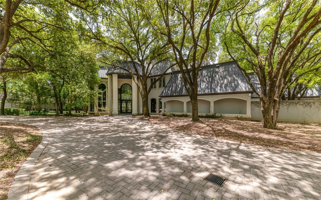 Set behind a privacy wall on approximately three acres of towering mature trees, this remarkable estate offers a level of seclusion rarely found while remaining conveniently positioned between Dallas and Fort Worth. Meandering stone pathways, a recirculating stream, and a canopy of mature oaks create an extraordinary landscape that feels more like a private nature preserve than a residence.Designed to embrace its surroundings, expansive walls of glass frame breathtaking views in every direction, filling the home with natural light and creating a seamless connection to the outdoors. The first-floor primary suite is a true retreat, featuring an expansive sitting area, an oversized walk-in closet, sauna, and a stunning spa-inspired bath where dramatic living moss walls create an unforgettable focal point beneath soaring windows overlooking the tree canopy.The recently updated kitchen blends timeless craftsmanship with modern finishes, featuring a Sub-Zero refrigerator, generous workspace, a service kitchen, and wine storage designed for effortless entertaining.More than a luxury residence, this is a home defined by its setting—a place where architecture and nature exist in quiet conversation, offering a level of privacy, tranquility, and beauty that is increasingly rare.The separate garage structure expands the property’s versatility with an oversized commercial kitchen and an impressive fitness center, creating exceptional space for entertaining, wellness, hobbies, or large-scale gatherings.