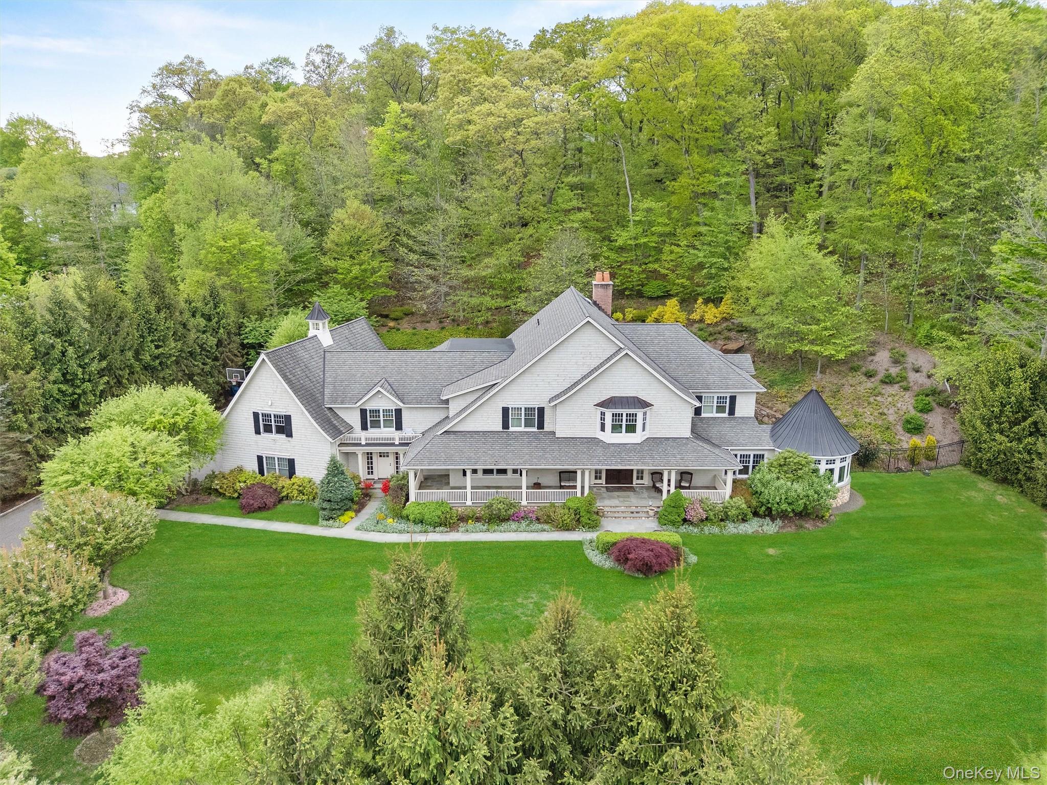 Welcome to this exceptional home where luxury and functionality meet. A bluestone walkway leads to a covered front porch with built-in heaters, setting the stage for refined living. Inside, a grand foyer opens to thoughtfully designed living spaces. The gourmet kitchen features an oversized island, 6-burner Wolf oven, Sub-Zero refrigerator and freezer, dual dishwashers, and a spacious walk-in pantry. A formal dining room with an adjacent butler’s area and sink makes entertaining seamless. The family room boasts coffered ceilings and a dual-sided wood-burning fireplace, opening through French doors to a covered outdoor sitting area. A formal living room and sunroom overlook mature landscaping, offering peaceful retreats. Additional highlights include a mudroom with built-in storage, laundry room, and access to a 4-bay garage, all designed for comfort and convenience.  Upstairs, retreat to the luxurious Primary Suite features a gas fireplace and two sets of French doors leading to a spacious private deck overlooking the backyard. The spa-inspired primary bath includes a soaking tub, walk-in shower, double vanity, private water closet, and dual expansive walk-in closets rooms with custom built-ins. Three additional en-suite bedrooms offer high ceilings and walk-in closets, providing comfort and privacy for all. A generous bonus room with its own powder room and a second laundry area completes the upper level, offering flexibility for recreation, work, or guest space.  An entertainer’s dream awaits on the lower level, featuring a spacious recreation area with a wet bar and sink, a dedicated movie room with theater seating, and a fitness room complete with a sauna, steam room, and spa area for ultimate relaxation. A powder room adds convenience, while a fifth en-suite bedroom provides a private retreat for guests or extended family.  The outdoor living space boasts an in-ground pool, built-in BBQ, and professionally landscaped gardens with custom lighting, offering a stunning backdrop for both relaxation and entertaining.