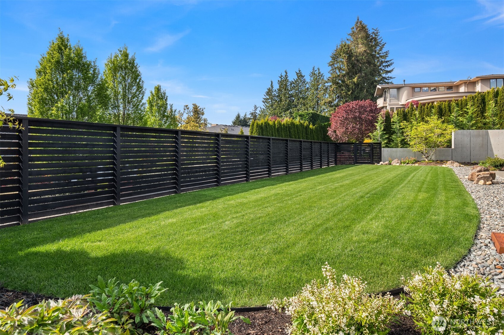 Expansive, level backyard with lush lawn and modern fencing.