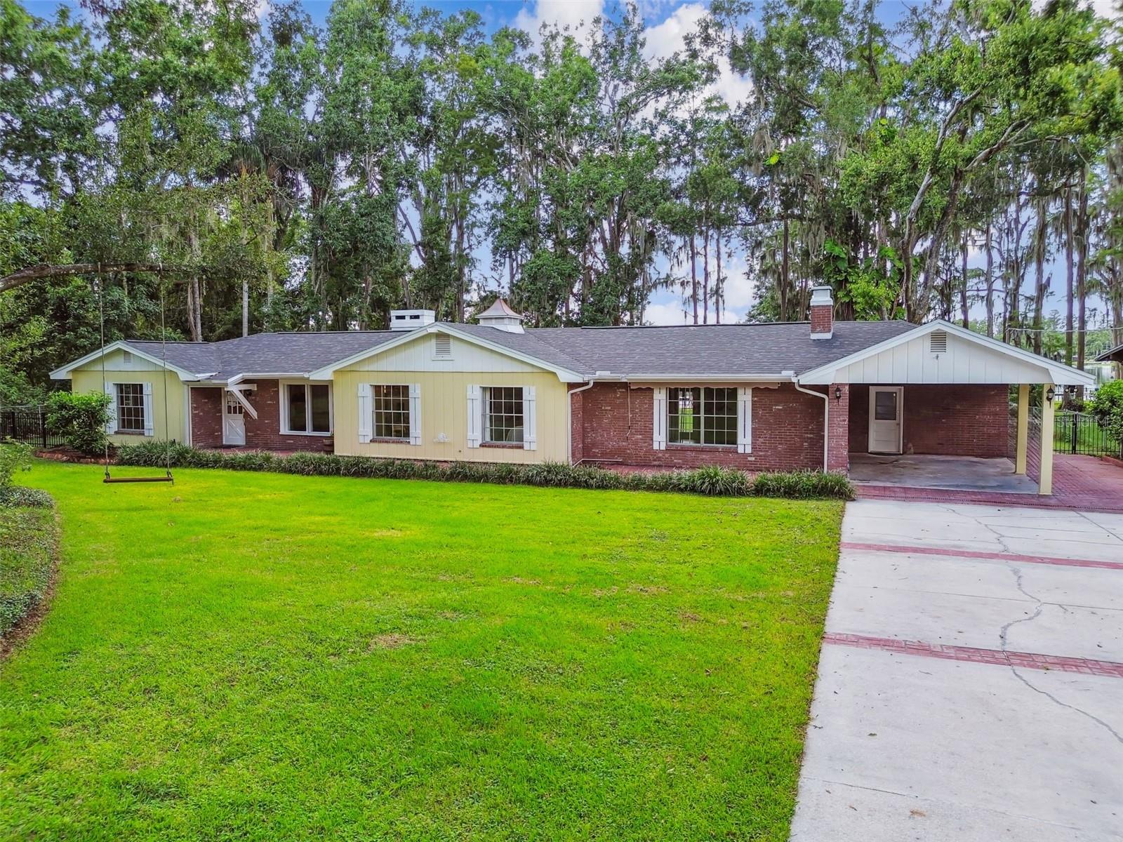 ONE OF A KIND LAKEFRONT HOME!  Welcome to this charming and picturesque one-story ranch-style home, perfectly situated on 1.12 ACRES of serene lakefront property. This stunning residence boasts 3 bedrooms, 2 bathrooms, and an expansive BONUS ROOM, offering over 2,400 square feet of luxurious living space. PRIME LOCATION with NO HOA! Enjoy the FREEDOM and CONVENIENCE of a prime location without the constraints of an HOA. As you pass through the gate, you'll be captivated by the long driveway, towering trees, and lovely brick façade that complement the spacious front yard. Step inside to discover the great room, featuring a soaring EXPOSED BEAM CEIING and a stunning WOOD-BURNING FIREPLACE, perfectly centered between double French doors that lead out to the screened lanai with BREATHTAKING LAKE VIEWS. The entire home is adorned with elegant WOOD-LOOK TILE flooring. The dining room, with its large window showcasing front yard views, offers ample space for gatherings of all sizes. The gourmet kitchen is a chef's dream, featuring quartz countertops, under-cabinet lighting, a pull-out pantry cabinet, stainless steel appliances, and abundant storage. The kitchen seamlessly opens to the breakfast nook, where a bright bay window overlooks the expansive backyard.  The generous primary suite offers premium views of Lake Holly and a private entrance to the patio. The adjoining bathroom features a soaking tub, separate shower, dual sinks, and a large linen closet just outside. The huge bonus room is incredibly versatile, perfect for a playroom, man cave, hobby room, or any other space you desire. The air-conditioned laundry room, conveniently located just outside the bonus room, provides ample space for both laundry and storage. The FULLY FENCED backyard, with 102 FEET of LAKE HOLLY FRONTAGE, is a magical retreat for enjoying with family, friends, and pets. Take a boat or kayak out on the lake, fish from the dock, or simply savor a cup of coffee while taking in the tranquil morning views or dazzling sunsets. Additional storage is available in the two storage sheds. This home is zoned for TOP SCHOOLS such as A-rated McKitrick Elementary, Martinez Middle, and Steinbrenner High Schools. Plus, enjoy peace of mind with a BRAND-NEW ROOF installed in 2025. Several new windows throughout the home!  Don't miss the opportunity to make this extraordinary lakefront home your own. Schedule your showing today and prepare to fall in love!