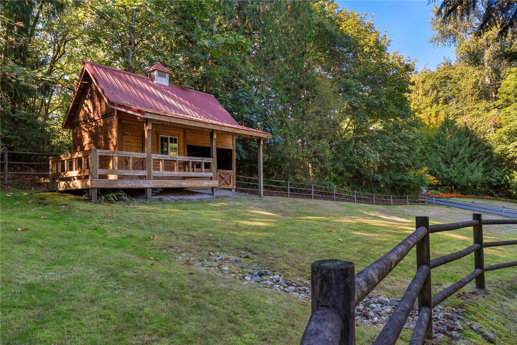 Wood barn strucutre with red metal roof and covered porch