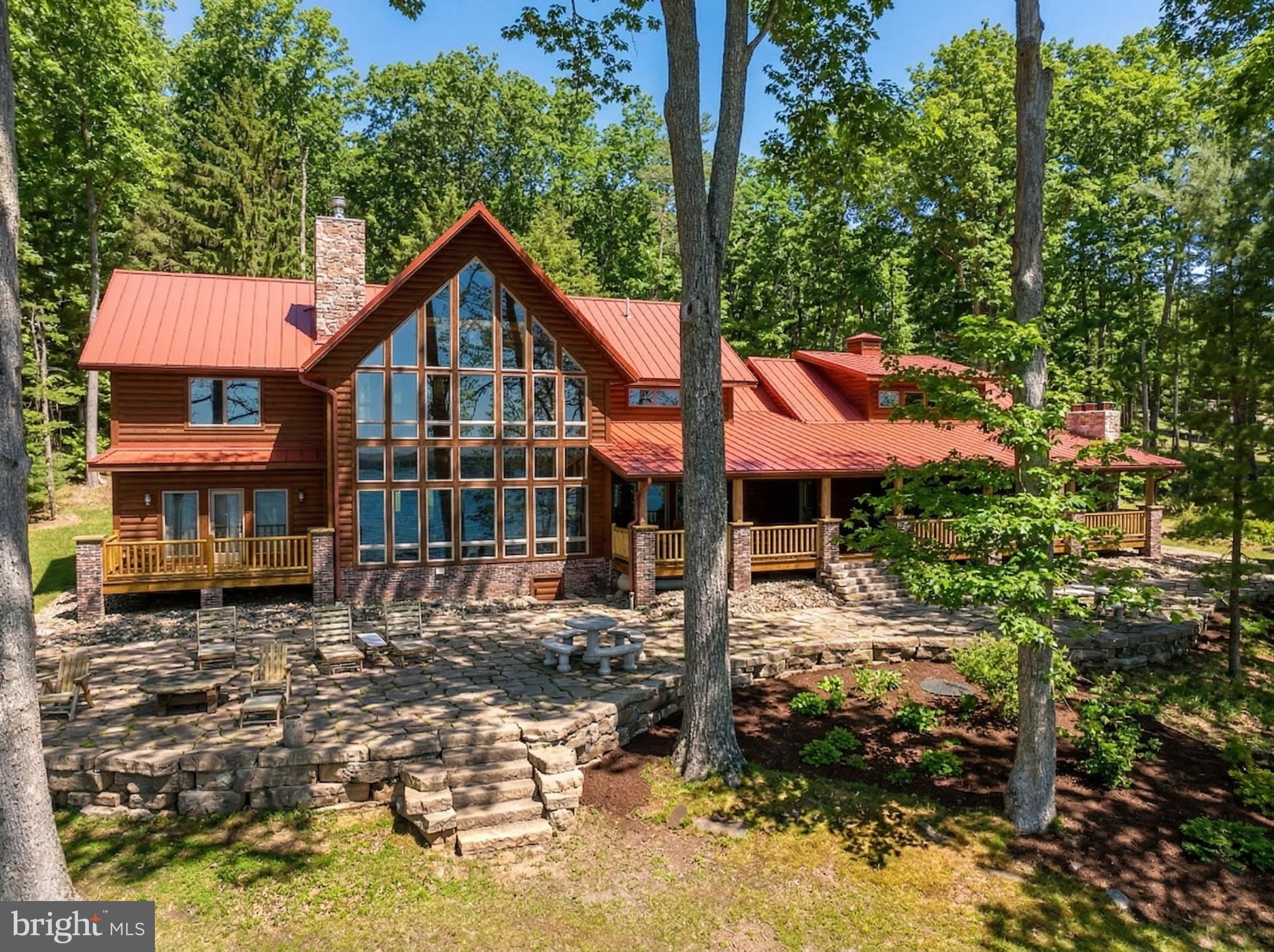 Stunning lakefront log home offering the perfect blend of rustic elegance and modern comfort. Boasting 181 feet of pristine waterfront, this 4-bedroom retreat features four en suite bedrooms. Three of the suites have their own fireplace that creates a warm, cozy ambiance throughout. The abundance of windows allows you to enjoy the beauty of the outside during any season from every level of this wonderful home. The open floorplan and upgraded kitchen feature an island and Corian countertops, providing ideal space to enjoy with family and friends. Enjoy breathtaking lake views from the expansive, covered outdoor deck, which also offers an outdoor fireplace—ideal for relaxing or entertaining year-round. The firepit and type A dock are just steps away and provide even more enjoyment. The central location on a dead-end road is unmatched, as are the gorgeous sunrises! This is a rare opportunity to own a private waterfront escape with exceptional charm and character.
