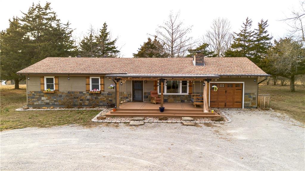 Tucked away on a quiet cul-de-sac just outside the city limits, this beautifully remodeled 3-bedroom, 2-bath residence sits on 1.9 acres in a highly desirable neighborhood and features a convenient circle drive for easy access and parking. Thoughtfully transformed from top to bottom. Inside, beautiful hardwood floors flow throughout much of the home, complimented by quartz countertops and a designer kitchen ideal for both daily living and entertaining. The kitchen showcases a farmhouse-style sink, a statement island with seating, and comes fully equipped with a refrigerator, gas range, exhaust hood, dishwasher, and built-in microwave, making it truly move-in ready. The inviting living area is anchored by a gas-insert brick fireplace, while the expansive sunroom, lined with windows and accented by a ceiling fan, offers a tranquil retreat and steps directly out to the patio and the chain-link fenced area, creating an effortless indoor-outdoor connection ideal for entertaining, kids, or pets. The primary suite offers a private retreat with a spa-inspired walk-in shower featuring a luxurious rain showerhead. A full unfinished basement provides exceptional storage or the opportunity for future living space. Outdoors, enjoy a spacious yard, the fenced area perfect for children or animals, a newly built pergola-style covered front deck finished with low-maintenance composite decking and bonfire area. Designed for relaxation, the deck features a full porch swing and two additional swings, creating the perfect setting for morning coffee or evening unwinding. Additional features include a 1-car attached garage and a detached 12x16 garage/outbuilding with concrete flooring, walk-in door, and garage door—ideal for a workshop or extra parking. This exceptional property offers refined upgrades, privacy, and convenient access to town.