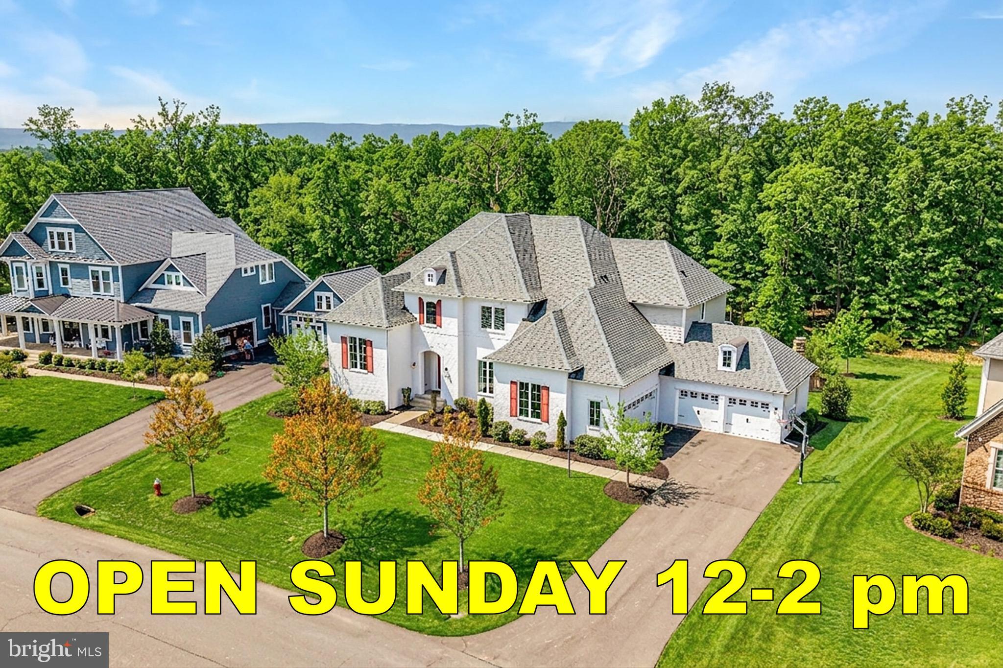 Quite simply, one of the finest homes in all of Willowsford. A rarely available Great Falls model by Drees Homes, this exceptional residence offers one of the largest floor plans in the community—boasting over 7,000 finished square feet and a commanding presence from the moment you arrive. Perfectly sited on a ½-acre lot backing to trees and protected conservancy land, the home showcases incredible curb appeal with its striking white brick façade, refined architectural detailing, and a welcoming covered front entry.Inside, a dramatic two-story foyer makes an unforgettable first impression, framed by a wide, elegantly appointed staircase, detailed moldings, and expansive windows that flood the space with natural light. Designer finishes and hand-scraped hardwood floors flow throughout, creating a seamless blend of sophistication and warmth. Formal living and dining rooms offer timeless spaces for entertaining, with the dining room beautifully anchored by a statement chandelier. Just off the staircase, a private home office provides a quiet and refined work-from-home retreat.The main living area is anchored by a stunning family room featuring a coffered ceiling, stone-surround gas fireplace, and custom built-ins—an inviting yet elevated space for everyday living. The gourmet kitchen is a true showpiece, thoughtfully designed with dual islands, high-end appliances, abundant cabinetry, and effortless flow into the sunlit breakfast room, highlighted by a designer light fixture. A butler’s pantry with wine storage enhances entertaining, while the expansive prep kitchen—complete with its own island and second washer/dryer hookup—offers unmatched functionality and organization.A main-level guest suite with a full bath provides exceptional flexibility for multigenerational living or extended stays. Upstairs, the luxurious primary suite is a private retreat, featuring a spacious sitting room and a spa-inspired bath with a freestanding soaking tub, a walk-through shower with dual shower heads, and separate vanities. Each additional upper-level bedroom is thoughtfully designed with its own en-suite bath and walk-in closet, while a conveniently located upper-level laundry room adds ease to daily living.The fully finished walk-up lower level continues to impress, offering a generous rec room, the 6th bedroom and full bath, and a versatile den ideal for a home theater, fitness studio, or hobby space. Outdoor living is equally exceptional, featuring a covered porch with ceiling-mounted heaters, a paver patio, and a fire pit, all set against a backdrop of peaceful wooded views—perfect for year-round enjoyment.Completing the home is a four-car garage—an exceptional feature that perfectly complements the home’s impressive scale and everyday functionality. Willowsford is Northern Virginia’s premier community, offering a one-of-a-kind lifestyle rooted in scenic beauty, sustainability, and farm-to-table living. Spanning 4,000 acres, this thoughtfully designed community features four distinct villages surrounded by preserved open spaces, lush forests, rolling meadows, and sustainable farmland maintained by the Willowsford Conservancy. Residents enjoy world-class amenities, including Sycamore House and The Lodge at Willow Lake, with resort-style pools, fitness centers, and farm-inspired culinary programs. An extensive trail network, a fishing lake, an amphitheater, a dog park, and nature-inspired recreational spaces further enhance the vibrant outdoor lifestyle. Conveniently located near major commuter routes, the Dulles Greenway, and the Metro Silver Line, Willowsford provides easy access to shopping, dining, and business hubs. It is also served by Loudoun County’s highly sought-after school system, making it an exceptional place to call home.