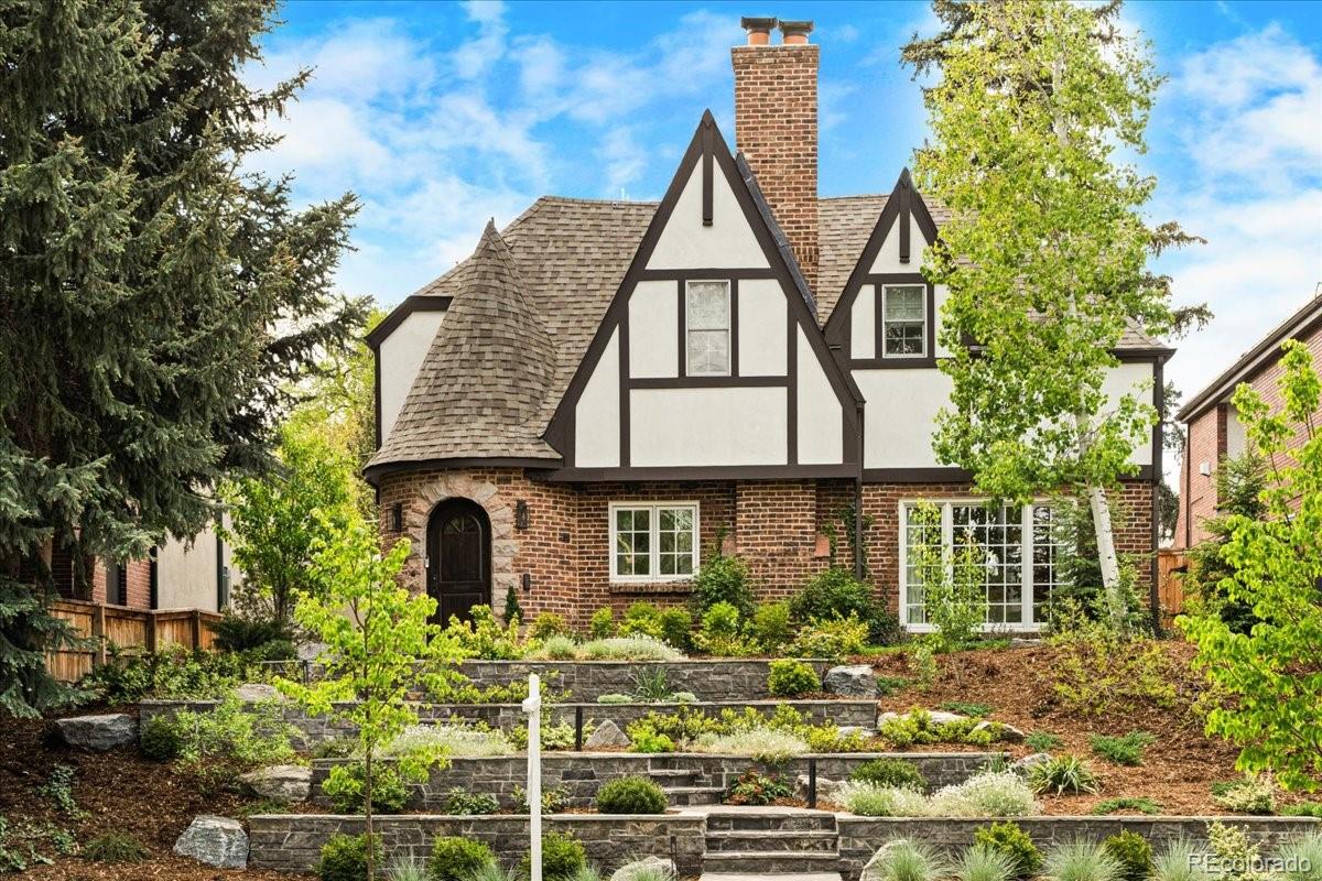 Set on an elevated lot along a quiet tree-lined block in Cherry Creek, 535 Garfield Street is a stunningly renovated Tudor Revival residence. Steeply pitched gables, decorative half-timbering, richly toned brickwork, a prominent chimney, and a round turreted entry with an arched wood door give the home storybook charm and curb appeal, along with its tiered stone retaining walls, flagstone paths, layered plantings, and mature trees. Inside, the main level is bright and open and finished with wide-plank oak floors, soft neutral tones, and an abundance of natural light. The kitchen serves as the center of the home, appointed with Miele appliances, an integrated refrigerator, honed granite countertops, and a spacious pantry. A dining room, living room with a wood-burning fireplace, and hidden bar make the main level the perfect place to dine, relax, and entertain. French doors from the dining room open directly to the flagstone patio and gorgeous back yard. A bedroom (currently set up as an additional living room), bathroom, and mud room complete the first floor. Upstairs, the primary suite occupies its own corner of the home with vaulted ceilings, French doors opening to a Juliet balcony, an adjoining room well-suited for a sitting area or office, and a full en suite bathroom with heated floors, a freestanding soaking tub, and a large glass-enclosed shower. Two additional bedrooms (one with an en suite), a full hallway bathroom, and laundry (washer/dryer included) complete the upper level. Completely turn-key! Updates include new windows, stucco, HVAC, water heater, plumbing/electrical, whole-house water filtration system, motorized crawl space access, and an electric dog door. The location is phenomenal with close proximity to amazing restaurants (Le Bilboquet, Matsuhisa, Barolo Grill, Uchiko, Alteno, etc.), shops, Congress and Cheesman Parks, the Botanic Gardens, and all that Cherry Creek offers. Schedule your private showing today! Buyer to verify all information.