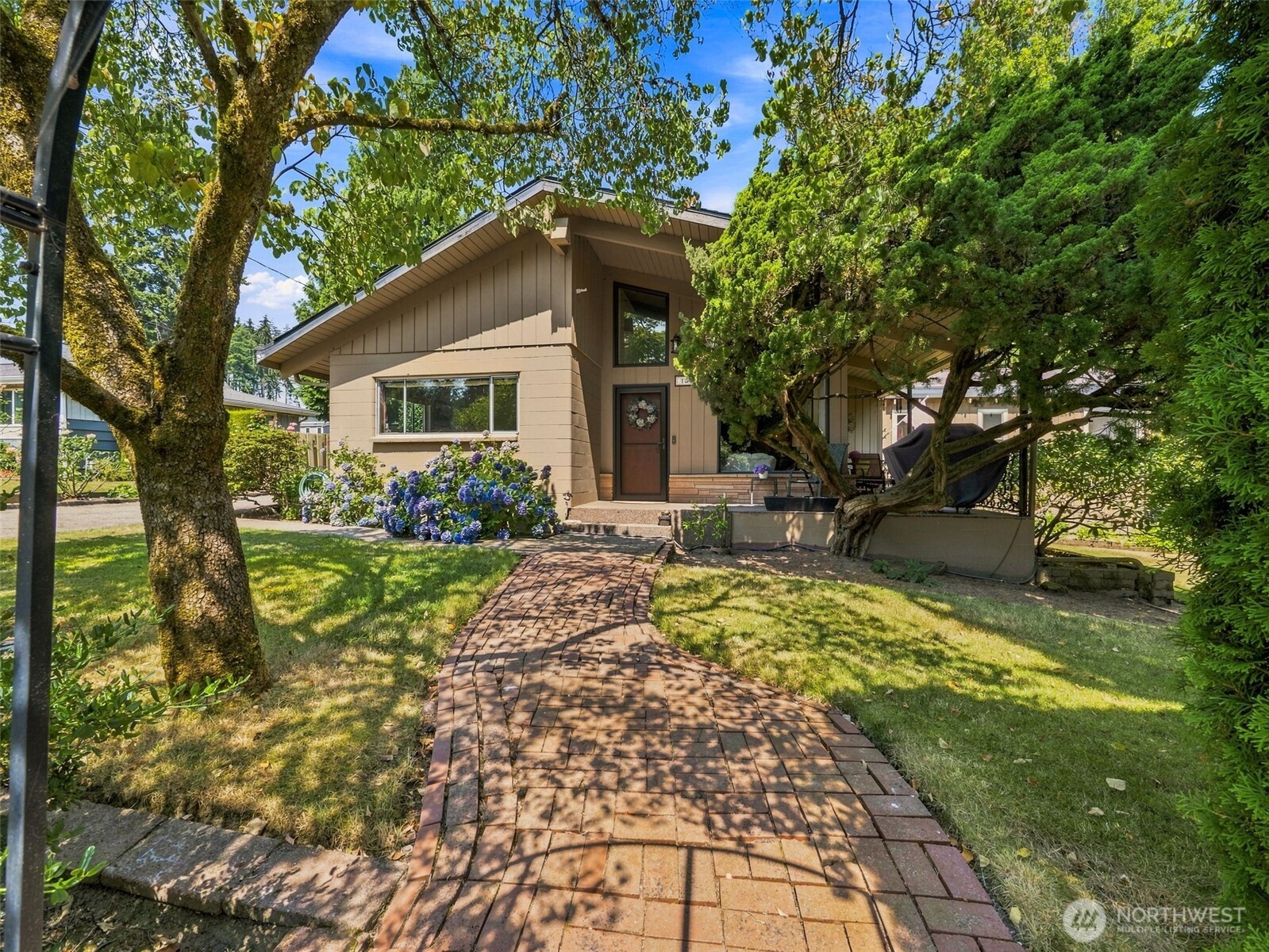 Mid-Century charm meets space, convenience, and a fantastic setting on this large corner lot in Burien. Vaulted ceilings and an incredible floor-to-ceiling brick fireplace create a striking first impression, while the oversized kitchen offers plenty of room to gather and entertain. With 3 bedrooms and 2 full baths, the home includes a spacious primary suite featuring a jetted tub for a relaxing retreat. Step outside to the expansive deck—truly an extension of the living space—overlooking the large, partially fenced lot and peaceful creek that does not flood. An oversized 2-car garage provides exceptional parking and storage. Enjoy easy freeway access without the freeway noise, convenient proximity to the airport, and all the restaurants, shops, amenities, and vibrant neighborhood downtown Burien has to offer. A special property offering character, breathing room, and exceptional accessibility.