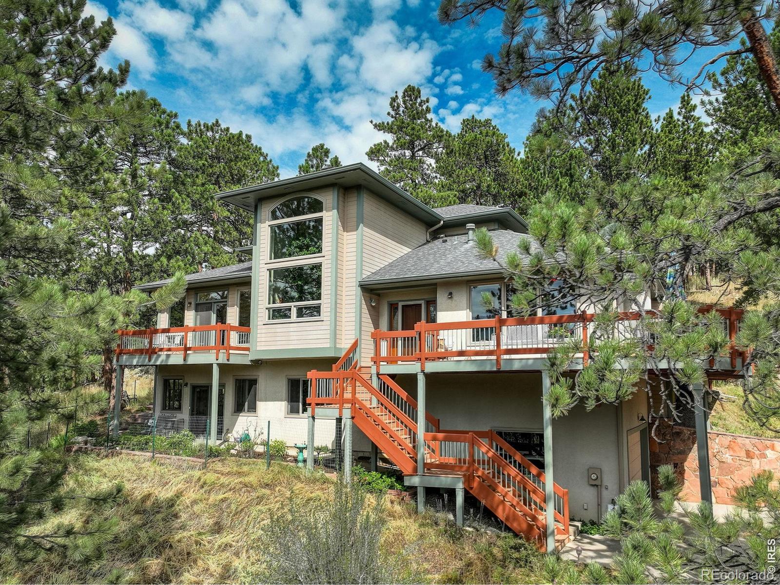 Betasso Vista Retreat - Ideally located just minutes from the Betasso Preserve, this exceptional mountain home offers easy access to miles of scenic trails while still being a short 10 minute drive to Downtown Boulder. Set on over an acre and framed by dramatic rock outcroppings, the property features expansive outdoor living spaces including flagstone patios, pink stone walkways, and a wraparound deck designed for seamless indoor-outdoor living, entertaining, and quiet retreat. Inside, soaring ceilings with ideal southern exposure fill the home with natural light throughout the day. The main level offers a thoughtful, highly livable layout anchored by a spacious primary suite with direct deck access, dual closets including a walk-in, and a luxurious five-piece bath with jetted soaking tub. The updated kitchen blends style and function with natural stone countertops, newer KitchenAid appliances, a glass tile backsplash, and a sunlit breakfast nook that flows seamlessly into the inviting family room with gas fireplace and wet bar-perfect for everyday living and hosting. Meticulously maintained and offered for the first time by its original owners, this home presents a rare opportunity to own a true mountain sanctuary. Recent improvements include refinished white ash wood flooring, a new furnace, new roof, and fire suppression system, along with the added convenience of a paved driveway and generator. The walk-out lower level offers a bright office and recreation room, both filled with natural light and flexible for work or relaxation. Perfectly south-facing with sweeping panoramic views, this exceptional property offers the rare combination of privacy, beauty, and proximity to the 800-acre Betasso Preserve with miles of hiking and biking trails. An extraordinary opportunity to enjoy the very best of mountain living, effortlessly close to town.