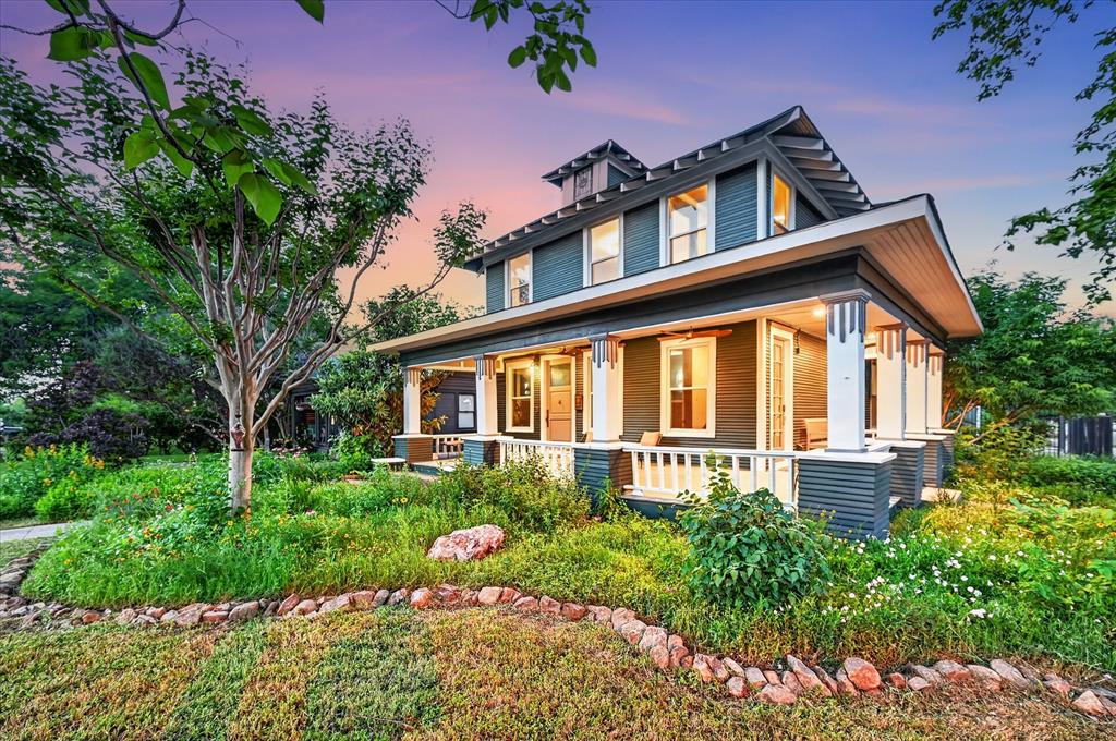 Kidd Springs Charm with Bishop Arts Lifestyle. This historic home built in 1918 with over a century of character, blends timeless architecture with thoughtful modern updates, located just blocks from the Bishop Arts District and Kidd Springs Park. Showcasing where early 1900s charm meets Art Deco influence, the home features moody tones, vintage hardware, designer lighting, and curated details that create a soulful, one-of-a-kind atmosphere. Oversized living spaces begin with a moody listening parlor, flowing into a flexible dining area, library or flex space that can easily function as a guest room with access to a full bath. The open-concept kitchen and living area offer a warm, inviting layout ideal for entertaining. Rich in history, the home highlights preserved early 1900s craftsmanship—from original doors and molding to thoughtfully maintained finishes—seamlessly paired with modern updates. Upstairs features a large living area that can serve as an extension of the primary suite. Down the hall, guest quarters, full bath, bedroom, and a light-filled sunroom—ideal for a yoga or workout space. Picture sitting back on wrap around front porch and taking in the established landscaping or stroll down to your favorite Bishop Arts restaurant. Detached garage with loft and rear space offers potential for a studio, guest quarters, or creative retreat.