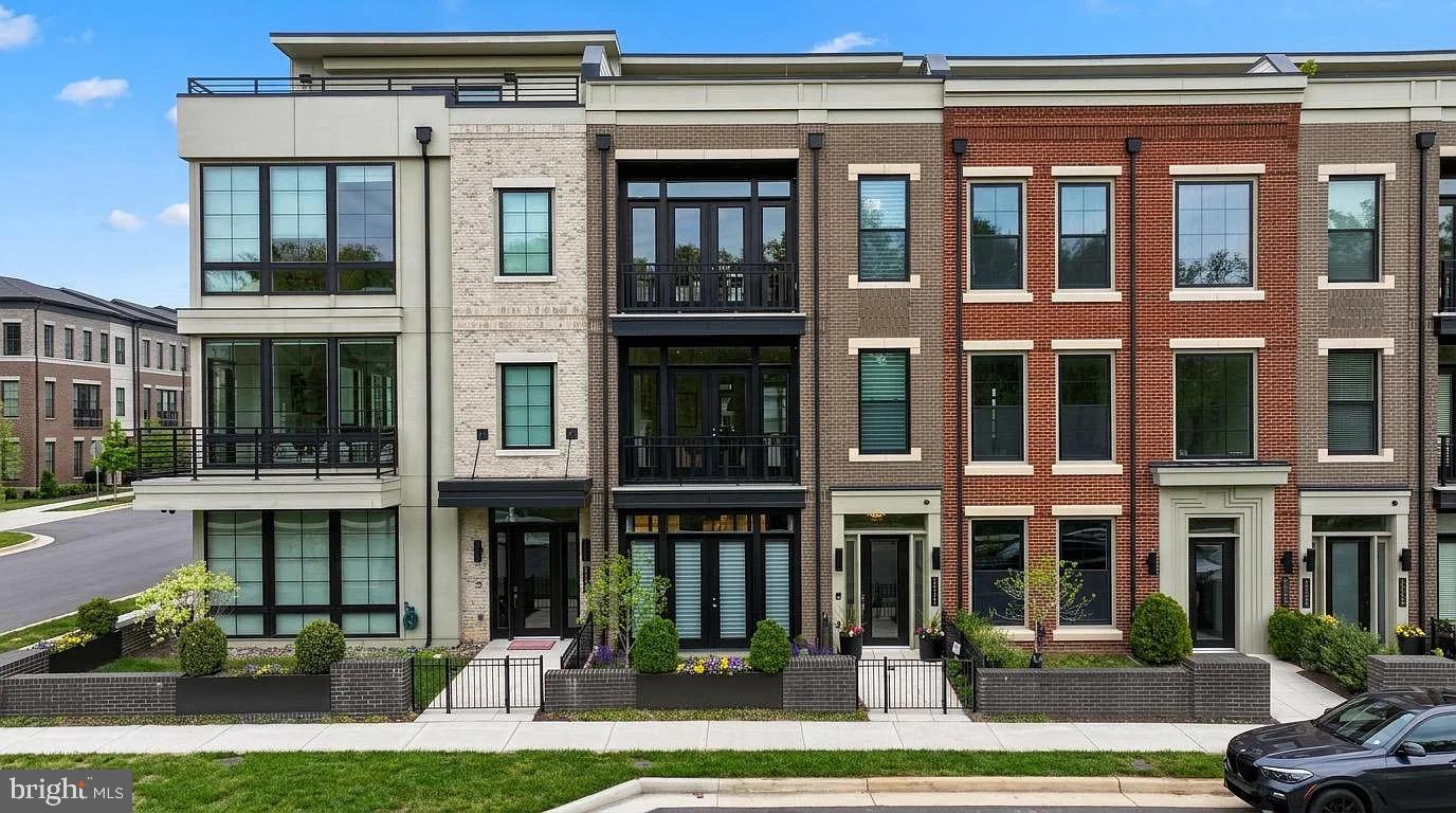 Welcome to one of One Loudoun’s most exceptional luxury townhomes—an ideal residence for those seeking to simplify without compromise. Perfectly positioned overlooking Central Park, this four-level home offers refined, turnkey living with the rare convenience of a private elevator connecting every floor. Thoughtfully designed for both everyday comfort and elegant entertaining, it delivers a seamless blend of sophistication, functionality, and effortless lifestyle.From the moment you enter, the home sets a distinctive tone. The entry level features an expansive club room with custom built-ins and a sleek wet bar with beverage refrigeration—an inviting space for hosting or relaxing. A fully built-out personal lobby provides exceptional storage, while dual-zone wine coolers (188-bottle capacity) offer a striking introduction to the level of detail found throughout.The main living level is a true showpiece, anchored by a chef-caliber kitchen designed to rival the finest custom homes. An oversized island, premium Wolf and Sub-Zero appliances—including a six-burner double oven range, convection steam oven, and dedicated wine tower—combine performance with striking design. Custom cabinetry, integrated lighting, and a designer backsplash complete the space. The sunlit dining and family rooms overlook Central Park, with a Juliet balcony enhancing the open feel. At the rear, a more intimate hearth room with gas fireplace opens directly to a private deck, creating a warm and versatile living environment.The bedroom level offers a serene retreat. The primary suite features custom-designed closets and a private balcony with peaceful park views. The spa-inspired bath includes heated floors, a walk-in shower, soaking tub, and elevated finishes throughout. Two additional bedrooms share a well-appointed bath, and a thoughtfully designed laundry room with custom built-ins adds convenience without sacrificing style.The top level is dedicated to elevated living and entertaining. A spacious recreation room with built-in surround sound is complemented by an impressive bar with refrigeration, creating an ideal gathering space. Step out to the expansive rooftop terrace, where a natural gas firepit and multiple seating and dining areas overlook the park—perfect for both relaxed evenings and larger gatherings. A fourth bedroom, full bath, and additional storage complete this level.What truly sets this home apart is its effortless, lock-and-leave lifestyle. With minimal exterior maintenance, elevator access to all levels, and fully integrated Control4 smart home technology for lighting, audio, and shades, every detail is designed for ease and comfort—whether at home or away.Located in the heart of One Loudoun, this residence offers unmatched walkability to premier dining, shopping, and entertainment. With convenient access to major routes, Washington Dulles International Airport, and Inova Loudoun Hospital just minutes away, it provides both connectivity and peace of mind.For those transitioning from larger homes or seeking a refined, low-maintenance lifestyle without sacrificing quality or space, this is a rare opportunity to enjoy luxury living in one of Northern Virginia’s most vibrant communities.This home truly has it all—don’t miss your opportunity to make it yours.