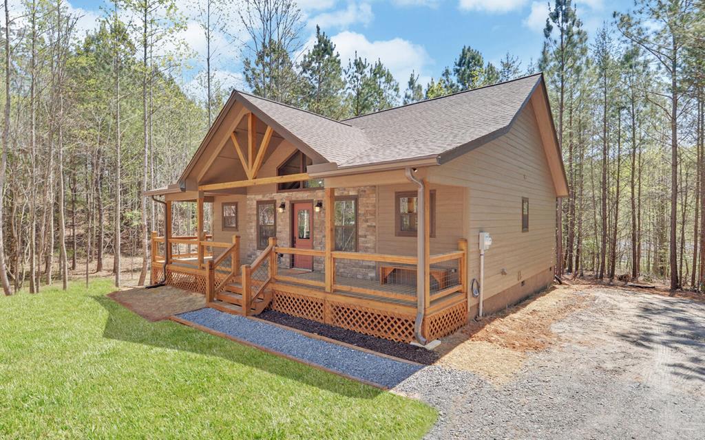 This new construction 2-bed, 2-bath cabin provides warm mountain character and low-maintenance peace of mind. Inside, vaulted ceilings open up the great room and kitchen, where a large island, fireplace, and rich wood floors, walls, and ceilings create the kind of cozy gathering space people actually remember. Thoughtful upgrades throughout set this home apart from the average new construction. Outside, the covered wraparound deck and firepit extend the living space and invite slow mornings and late-night conversations under the stars. Shared well, septic, and ample parking complete the package. Set on 1 acre and positioned near-equidistant between downtown Murphy and McCaysville, GA, it makes weekend escapes, dining, shopping, and outdoor adventure easy.