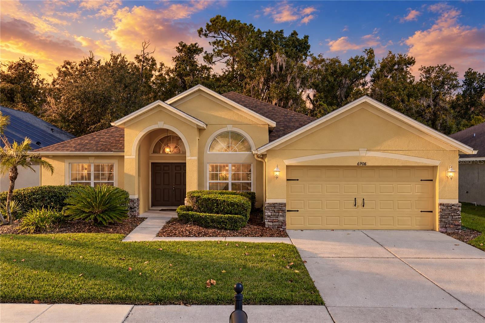 Virtually Staged. It's hard to believe you are so close to the conveniences of Wesley Chapel when your backyard overlooks such a beautiful conservation setting! Within the amenity-filled Oak Creek community, this 3 bedroom, 2 bath home with a dedicated office enjoys an expansive fenced backyard, an extended screened lanai, and a floor plan with room to make it your own. Even better, the major updates are already taken care of with a 2023 roof, a 2022 AC, and new laminate flooring throughout most of the home! Sidewalk-lined streets, mature landscaping, and a covered entryway welcome you into a versatile interior with a neutral color palette and a wonderful amount of living space. Near the front of the home, a dedicated office sits behind French doors with a ceiling fan overhead, creating a private workspace away from the main living areas. An oversized formal dining room is nearby, ready for holiday gatherings and special occasions. Just beyond, the spacious living room opens beneath high vaulted ceilings, with built-in surround sound speakers, triple sliding glass doors to the lanai, and an open view into the kitchen. Whether you love cooking for a crowd or simply appreciate a kitchen with room to move, this one has plenty to offer! Generous countertops, a central island with additional storage, breakfast bar seating, and a walk-in pantry give you excellent flexibility. Stainless steel appliances include a new refrigerator and a double-oven range, while a charming casual dining nook provides another comfortable place to enjoy meals. The laundry room and garage entry are conveniently located nearby, making unloading groceries and keeping up with household tasks a little easier. Privately separated from the secondary bedrooms, the generously sized primary suite features a distinctive open-style ensuite bathroom accented by an architectural glass-block wall. Dual sinks, a separate jetted soaking tub, a private water closet, and a spacious walk-in closet complete the retreat. Across the home, bedrooms 2 and 3 are comfortably sized and sit near the second full bathroom, featuring a tub/shower combination and direct access to the screened lanai. The backyard may just become your favorite part of the property! An extended screened lanai with built-in surround sound speakers overlooks the generous fenced lawn and beautiful conservation scenery beyond. Whether enjoying your morning coffee or spending an evening outside, the natural backdrop creates a wonderful sense of separation from the activity of the surrounding area. Additional improvements include spray foam insulation in the exterior block walls, double-pane windows with 3M hurricane-strength film, and a 50-gallon water heater installed in 2016. Oak Creek residents have access to a community swimming pool, playground, dog park, basketball court, and covered seating areas. Conveniently located between Wesley Chapel and Zephyrhills, the community keeps local shopping, dining, and entertainment within easy reach while this home gives you a beautiful place to escape the bustle. Call today to schedule your private showing and see why this home deserves a closer look!