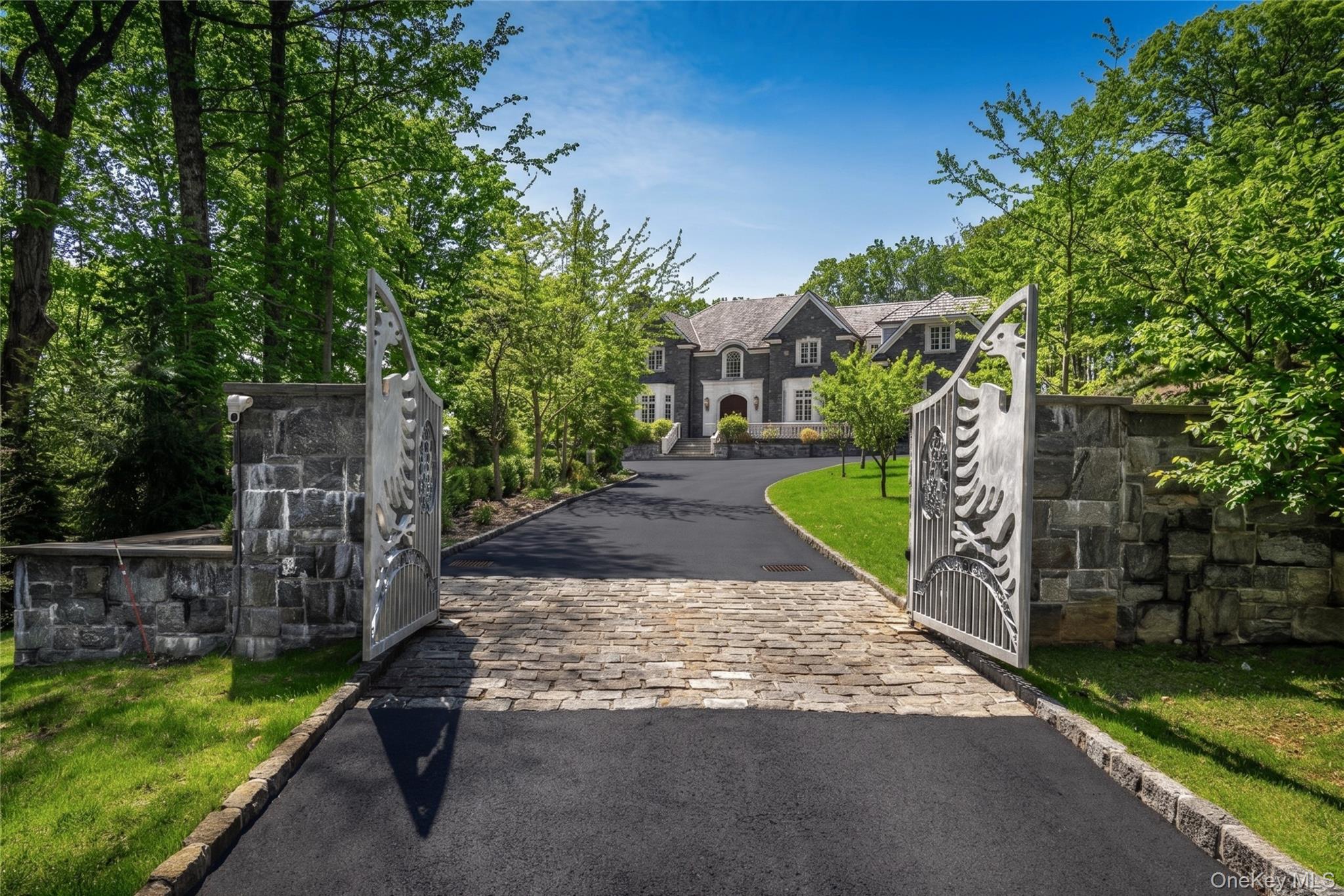 Set within one of Armonk’s most sought-after locations, this exceptional custom-built stone Colonial offers a rare combination of privacy, scale, and refined craftsmanship. Privately positioned behind a gated entrance on nearly five level acres, the property showcases sweeping lawns, newly designed landscaping, and breathtaking open vistas—creating an ideal setting for both everyday living and grand entertaining.A dramatic entry introduces the home’s impressive interior, highlighted by a striking double floating staircase and a sun-filled, two-story living room with radiant heated floors. The thoughtfully designed open layout seamlessly connects formal and informal spaces, offering both elegance and comfort. At the heart of the home, the chef’s kitchen flows effortlessly into inviting gathering areas centered around a timeless stone fireplace, with French doors leading out to an expansive stone patio complete with its own outdoor fireplace.The grounds are equally impressive, featuring a wide, usable backyard perfect for recreation or future enhancements, including an ideal pool site. Whether hosting large gatherings or enjoying a quiet afternoon, the outdoor spaces offer endless possibilities.Inside, the home features two luxurious primary suites—one on the main level and one upstairs—along with two additional bedrooms. Six full bathrooms and two powder rooms are beautifully appointed with high-end finishes, including marble baths, soaking tubs, and steam showers.The walk-out lower level is designed for both work and leisure, offering a spacious office, fireplace, home theater, and an elegant wine cellar. Additional highlights include radiant heated floors in select areas, abundant storage, and a heated three-car attached garage.Located just minutes from the heart of Armonk, with easy access to major roadways, Westchester Airport, and the North White Plains train station, this home combines serene estate living with everyday convenience. All within the award-winning Byram Hills School District.
