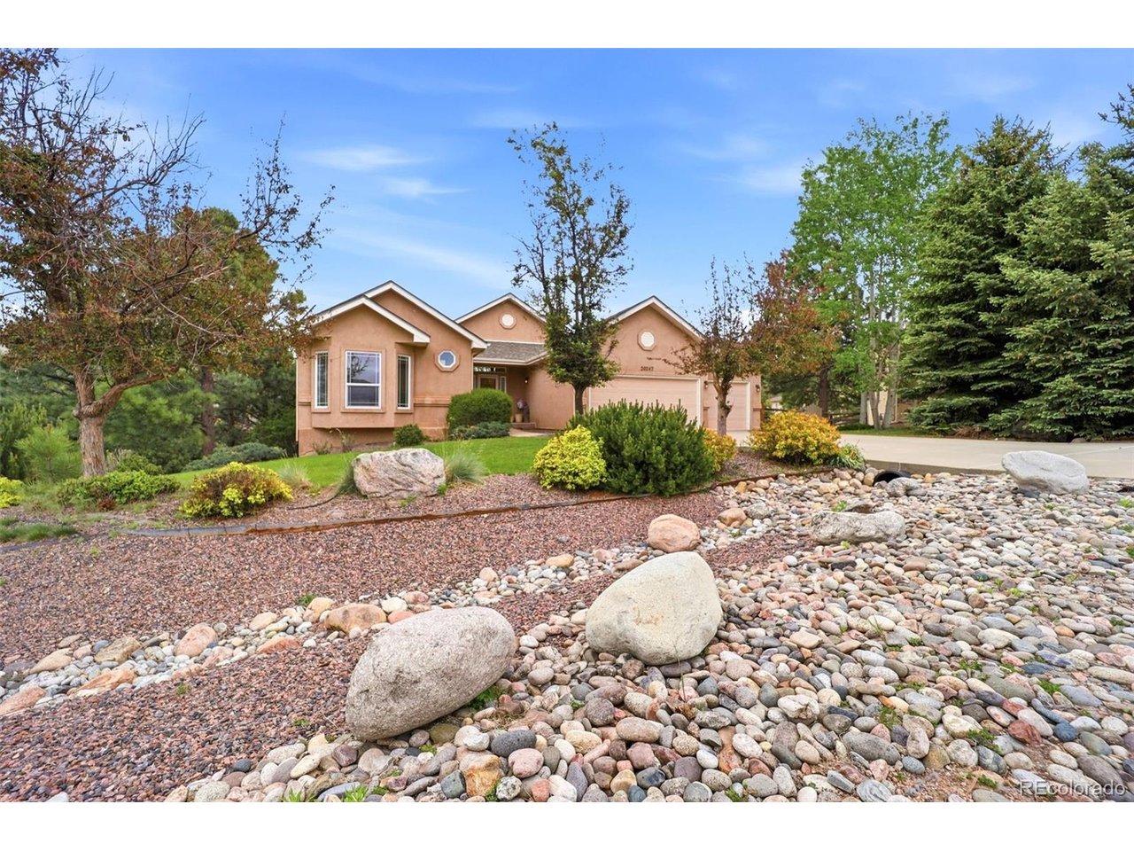 Experience elevated Colorado living in this exceptional ranch-style home nestled atop scenic Monument Hill. Surrounded by towering pines, dramatic rock formations, and expansive mountain views, this property offers the perfect combination of privacy, comfort, and accessibility- all just minutes from I-25 with convenient access to Colorado Springs, Denver, and DIA. Designed for effortless one-level living, the main level welcomes you with soaring vaulted ceilings, abundant natural light, and a spacious open layout that perfectly captures the beauty of the surrounding landscape. Large windows frame the incredible scenery, creating a warm and inviting atmosphere throughout the home. At the center of it all is a beautifully appointed kitchen built for both everyday living and memorable gatherings. Featuring quartz countertops, upgraded 42" cabinets, a stainless steel farmhouse sink, gas cooktop, and double ovens, this space blends style and functionality while offering plenty of room to cook, entertain, and connect. With 5 generously sized bedrooms, there is ample space for guests, home offices, hobbies, or growing households. The finished walk-out basement with impressive 9-foot ceilings expands the living space even further, offering endless possibilities for recreation, entertaining, or multi-generational living. The setting feels peaceful and secluded, yet remains close to everything you need- from shopping and dining to hiking trails, outdoor adventures, and everyday conveniences. Whether you are enjoying crisp mountain mornings, relaxing evenings under the trees, or taking in the ever-changing Colorado skies, this home delivers a lifestyle that feels both refined and refreshing. Additional recent improvements add comfort and peace of mind, including a new furnace and air conditioner (2025), water softener (2025), radon mitigation system (2025), living room ceiling fan (2025), and reverse-osmosis water filtration system in the kitchen (2026).