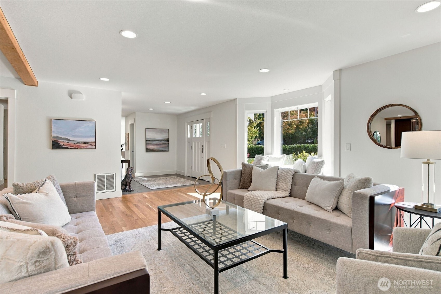 The living room flows from the entry in one uninterrupted space of warm hardwood and bright walls.