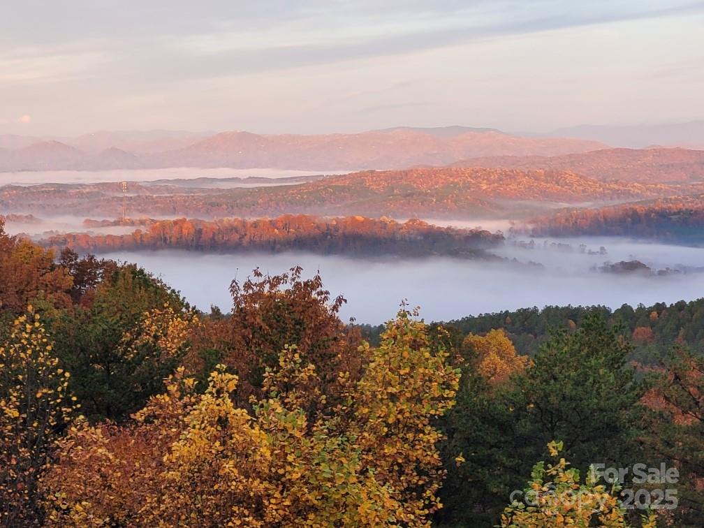 146 Sarinac Drive offers 4,120 square feet of refined mountain living across three finished levels, built in 2019 and set on a wooded 3.97-acre property with year-round, long-range western mountain views. Constructed with white pine half-log siding, LP SmartSide, Superior Walls foundation, metal roof accents, and Cardinal windows, the home reflects quality materials inside and out. The main level features 8-inch engineered hickory hardwood flooring and a vaulted tongue-and-groove ceiling in the great room. A wall of windows anchors the space, along with a rock gas fireplace featuring copper accents, a raised hearth, and wood beam mantle. French doors lead to a large back deck with cable railing and cedar beam details. The kitchen includes a bay window over the sink, granite countertops, shaker-style maple cabinetry with pantry pullouts, subway tile backsplash, stainless appliances to include a gas range with griddle, Samsung refrigerator, Bosch dishwasher and GE microwave. The main-floor primary suite includes deck access, shiplap walls, ceiling fan, walk-in closet, and a full bathroom with granite counters, dual vanity with makeup area, semi-frameless tile shower with body jets, rain head, handheld, built-in bench, cubbies, and a private water closet with bidet. A powder room and laundry room complete the level. The upper floor features a Douglas fir staircase with spacious landing, an open loft with railing overlooking the great room, two bedrooms (one with a walk-in closet), a full bath with dual marble vanities, linen storage, and a shower/tub combination. The lower level includes vinyl plank flooring, two large flex spaces, a full bath with granite vanity and tiled shower/tub, an additional bedroom with walk-in closet, an unfinished storage/mechanical room with shelving, and walk-out access to a covered patio. Stairs lead to the gravel fire pit area and up to the garage. Exterior living spaces include a wraparound porch with cable railing and a tongue-and-groove ceiling, screened porch with a rock wood-burning fireplace and dual access to the deck and great room. The expansive back deck offers westward mountain views and seamless access from the primary bedroom, great room, and screened porch. To learn more about this exceptional property or to schedule a private showing, please reach out to the listing agent with any questions. HOA dues are $720 as the property is made up of two combined lots ($360 yearly x 2).