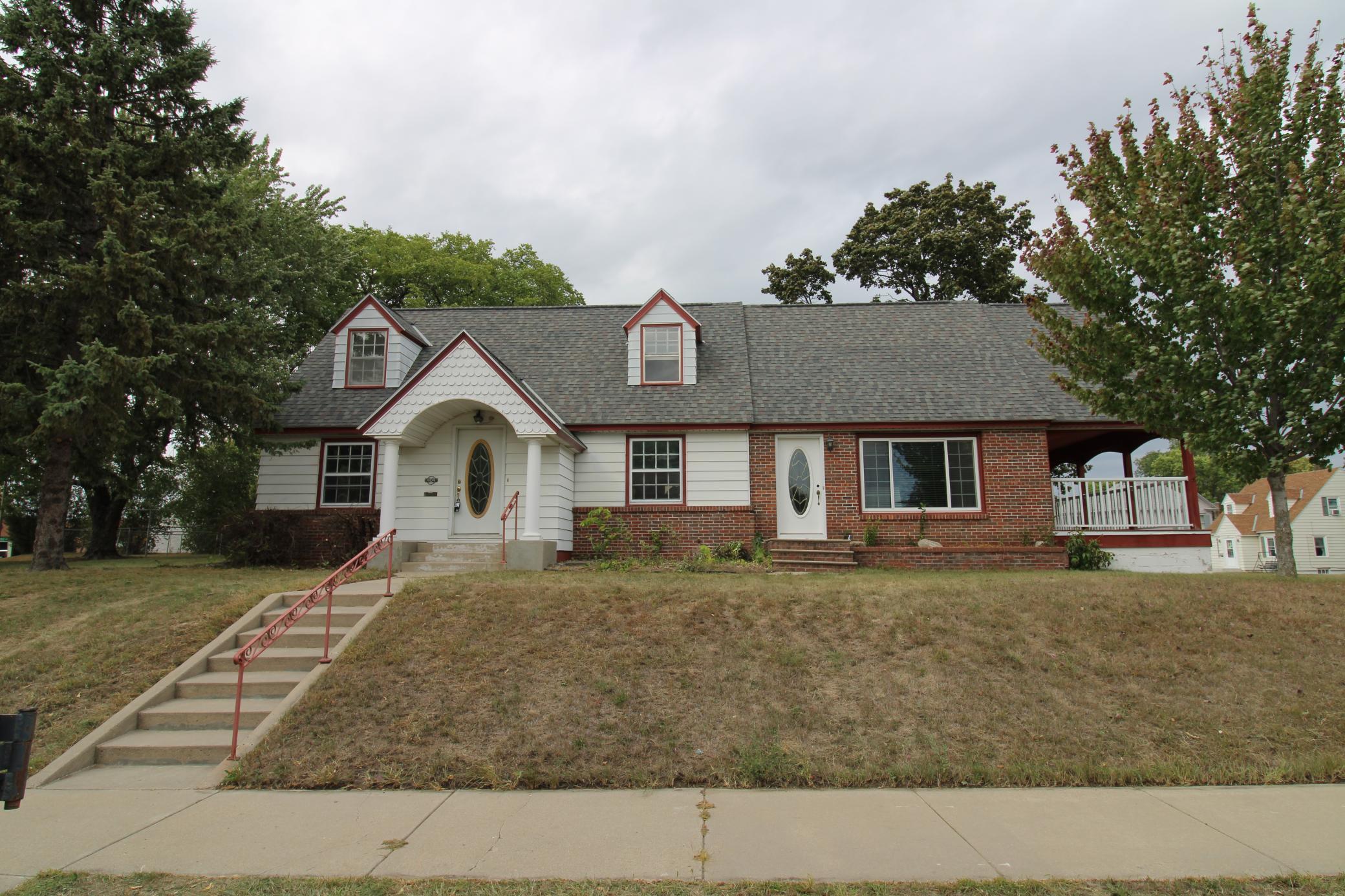 Welcome to this well-maintained 1 ½ story home situated on a desirable corner lot, featuring durable metal siding and brick exterior. This 3 bedroom, 1.5 bath home offers a ton of square footage for the price, with real hardwood floors and an impressive 19' x 22' living room complemented by a cozy wood fireplace. The main floor includes a bedroom and laundry hook-ups for convenient one-level living, while upstairs you'll find a huge bedroom with a walk-in closet. Recent updates include fresh paint, new luxury vinyl plank flooring and carpet, and new roads and sidewalks — all paid for. Enjoy outdoor living on the 10x24' covered porch with composite deck, and take advantage of the impressive storage space with a 2 car attached garage and 1 car detached garage.