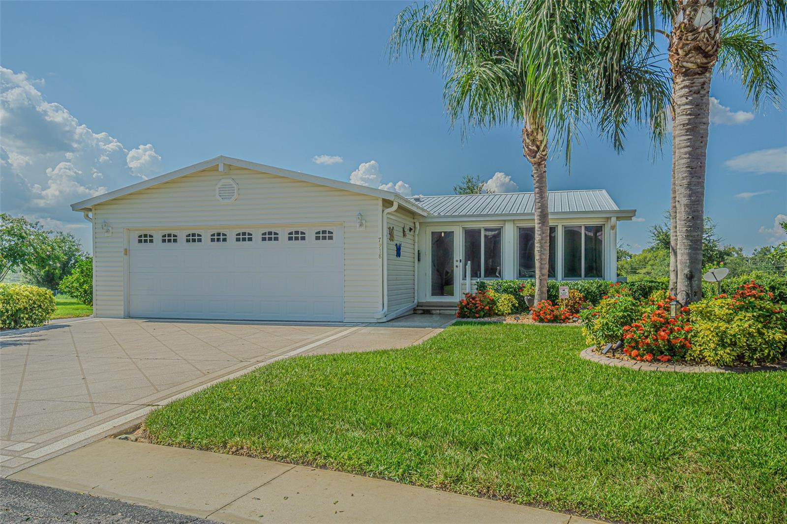 Welcome to this beautifully maintained custom home nestled in the highly sought after 55+ GATED community of Grand Horizons, where you OWN Your LAND!  Located on a quiet cul-de-sac, this residence sits on a PREMIUM oversized pie-shaped lot, offering serene views of rolling hills and lush greenspace.  Enjoy Florida living year-round from the comfort of your enclosed front porch, complete with air conditioning and slider windows — the perfect space for morning coffee or afternoon relaxation.  Great Curb appeal greets you with mature tropical landscaping!  Once inside the storm door, find elegant wood flooring flowing through the foyer, hallway, kitchen and laundry room, while upgraded carpeting graces the other areas for both style and durability.  The light and bright open-concept floorplan connects the kitchen, living, and dining areas, creating an inviting space, ideal for entertaining.  The kitchen features a breakfast bar, stainless and black appliances, stone backsplash plus ample cabinetry.  Sliding doors from the Great room OPEN to a generously sized Florida Sunroom at the rear of the home, enclosed with glass windows and offering a separate exit to the private side yard... a tranquil retreat to enjoy nature in peace.  This thoughtfully designed home offers two bedrooms plus a versatile den/office with French doors just off the foyer — easily convertible into a third bedroom if needed.  The owner’s retreat is located at the rear of the home for privacy and includes a spacious ensuite bathroom.  The secondary bedroom and full bath are situated at the front of the home, perfect for guests.  Additional features include a large interior laundry room with storage closet, generous closet space throughout, plus a two-car garage.  Live the Life in this active 55+ community!  Residents of Grand Horizons enjoy access to a resident-owned clubhouse featuring a billiards room, craft room, library, dining area, and a commercial-grade kitchen.  Amenities also include a heated pool and a calendar full of social events, onsite dinners, shows, travel excursions, and planned activiities — all with low monthly HOA fees and no CDD fees.  Located in East Pasco county in the HILLS of Zephyrhills, just minutes from medical facilities, restaurants, shopping, YMCA, theater, bowling and major highways for easy commute to Wesley Chapel malls and outlets, Tampa, Ocala, Orlando, Lakeland, Airports and the Beaches!  Don’t miss your opportunity to own this special home in one of the area’s premier adult communities.  CALL TODAY!